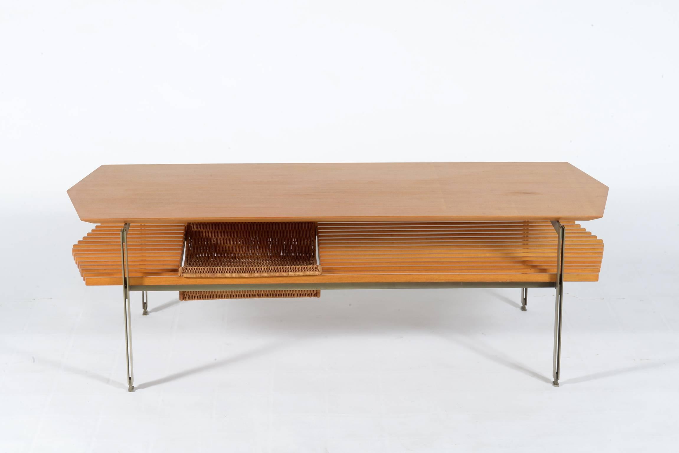 Italian 1960s wood and chrome metal coffee table.
The tabletop has a particular shape, in the lower level there is a rattan magazine rack.
 