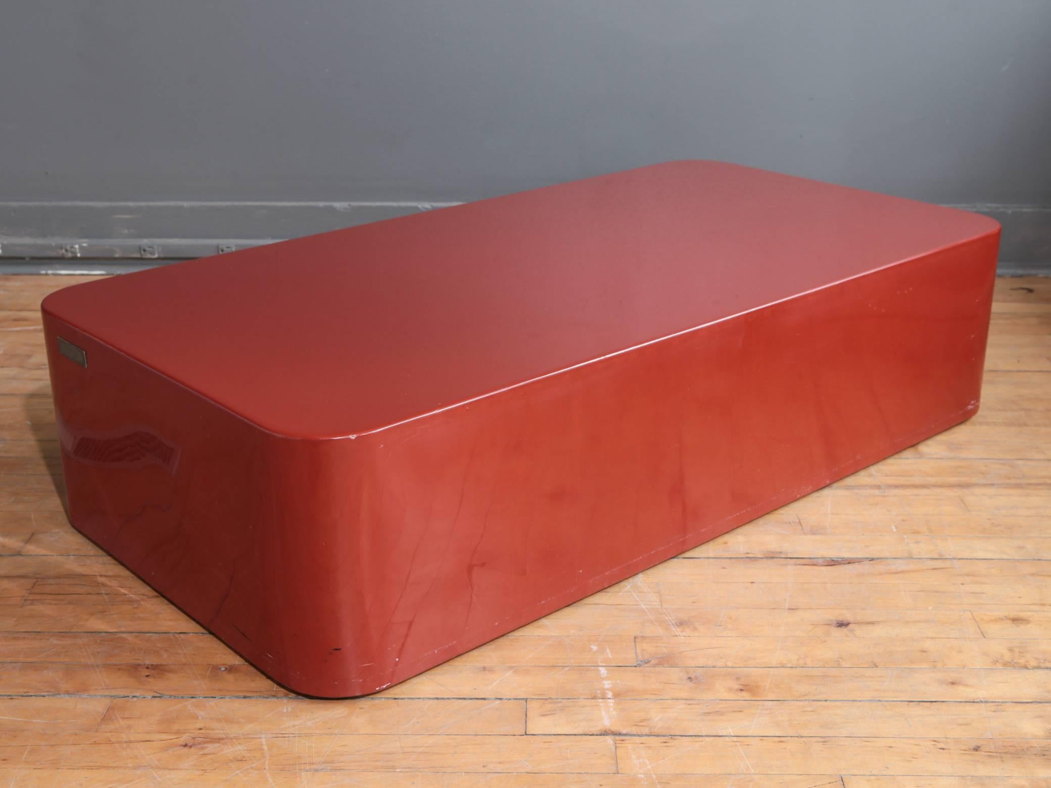 A rectangular coffee or cocktail table designed by Giacomo Passera, circa 1970s. Consisting of poured lacquer over a wood frame finished to a cinnabar red. Original brass label with facsimile Giocomo Passera signature present. Marked "Made in