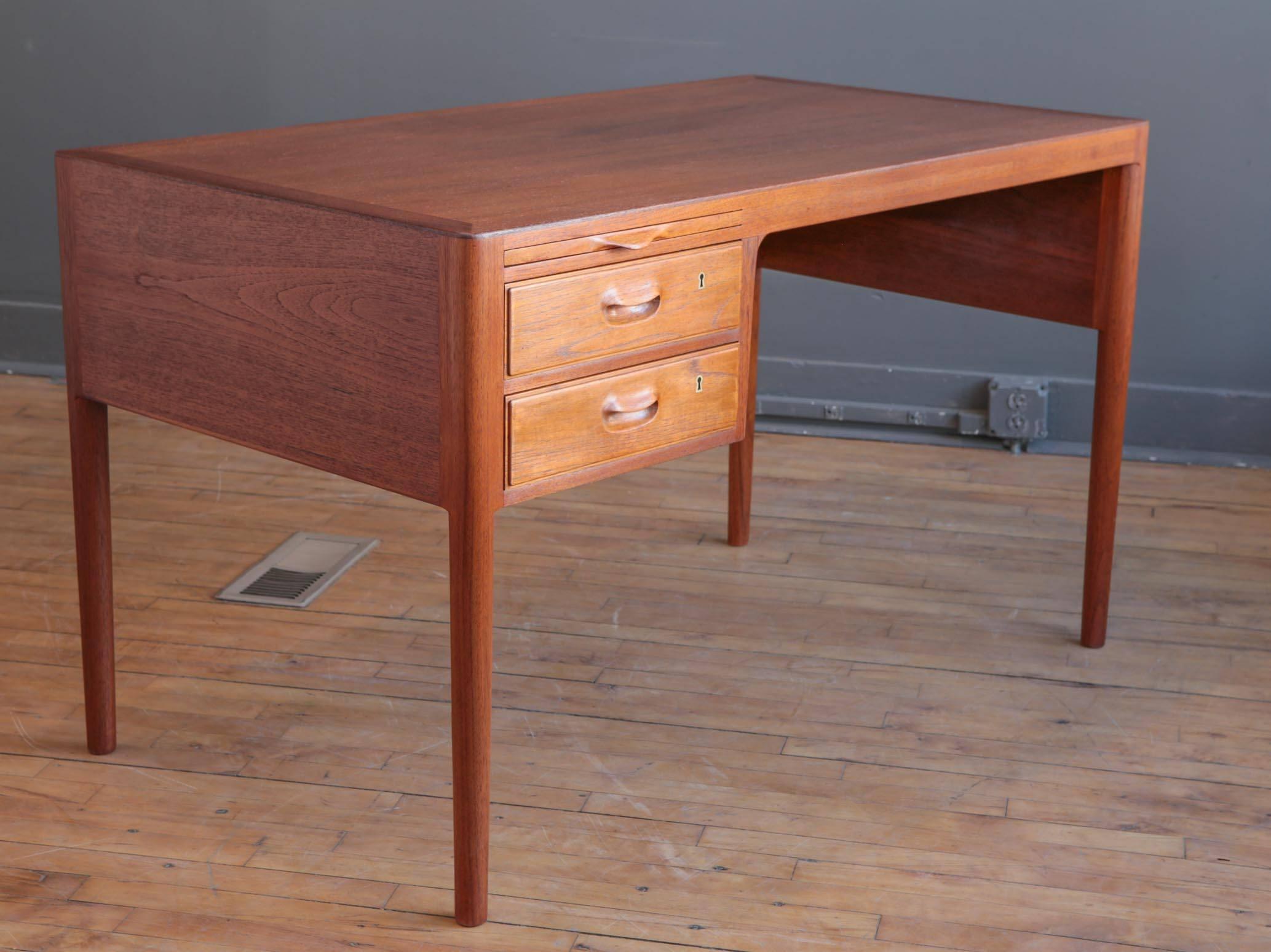 A seldom seen teak writing desk by Danish designer Hans Wegner for Johannes Hansen, circa 1960s. Featuring two locking drawers with sculpted handles and pull-out writing surface. Turned legs and subtle details enhance Classic, well-proportioned