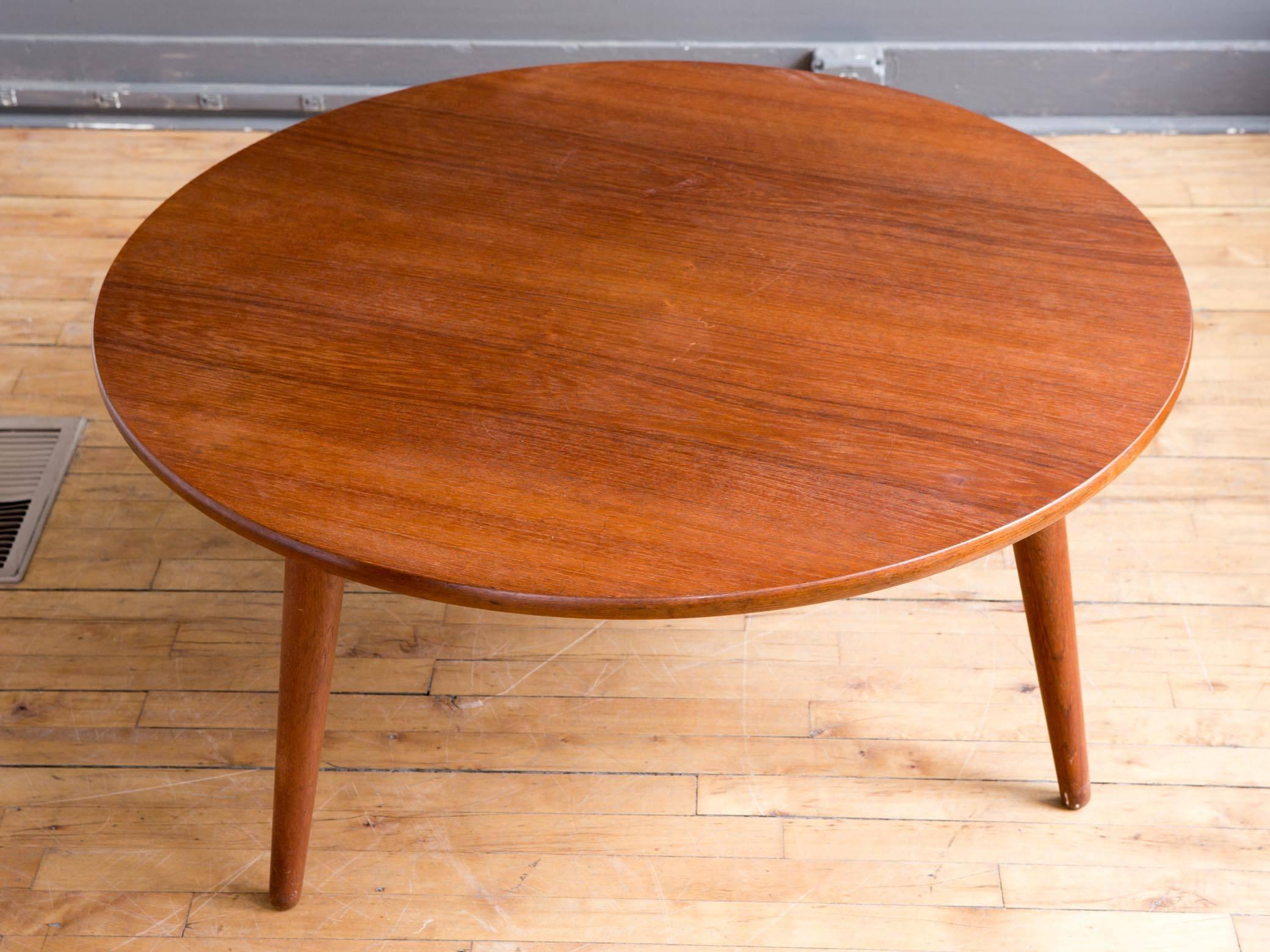 A teak coffee or cocktail table designed by Hans Wegner, circa 1950s. Manufactured by Andreas Tuck. Featuring a generous circular top with attractive graining supported by three conical splayed legs. Branded manufacturer's mark to underside.