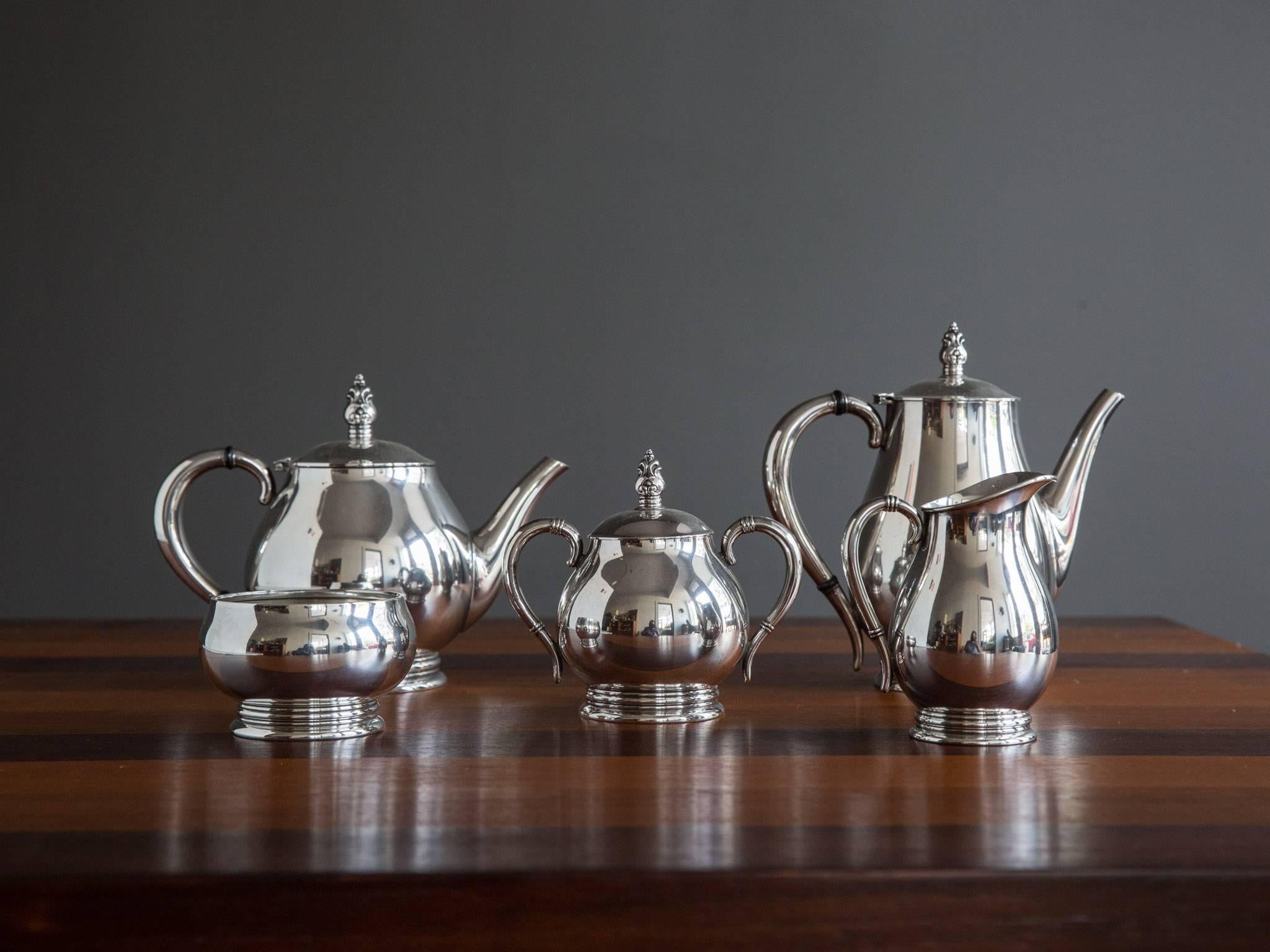 A five-piece sterling silver coffee and tea service in the "Royal Danish" pattern by International Silver, circa 1940s or 1950s. Featuring a coffee pot, tea pot, cream/milk jug, covered sugar bowl, and waste bowl. The coffee pot, tea pot