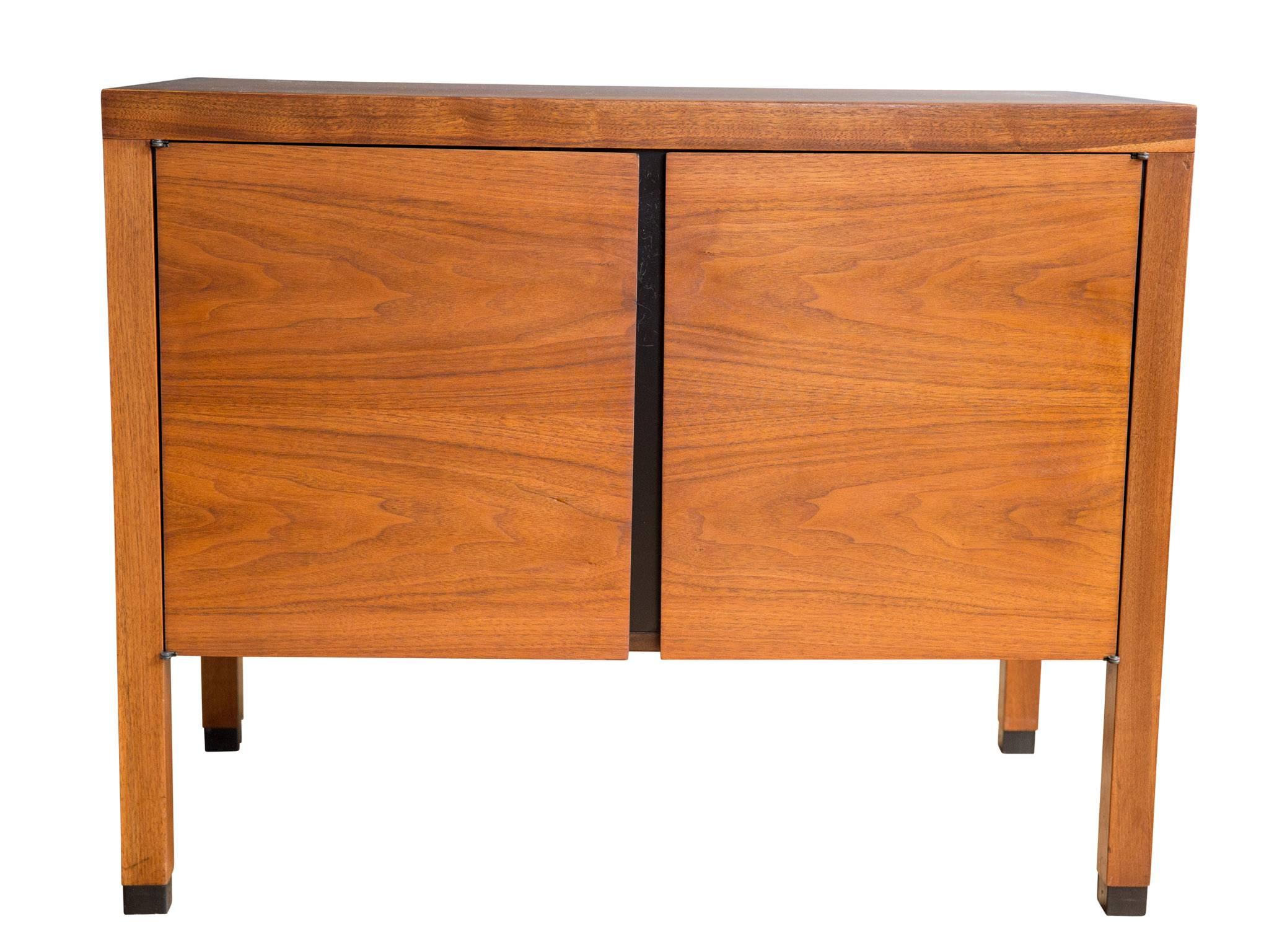 A quietly elegant walnut cabinet attributed to Paul McCobb for Directional Furniture, circa 1960s. Featuring two doors with recessed pulls that open to reveal adjustable shelving. Carefully matched graining, handsome capped legs, and a finished back