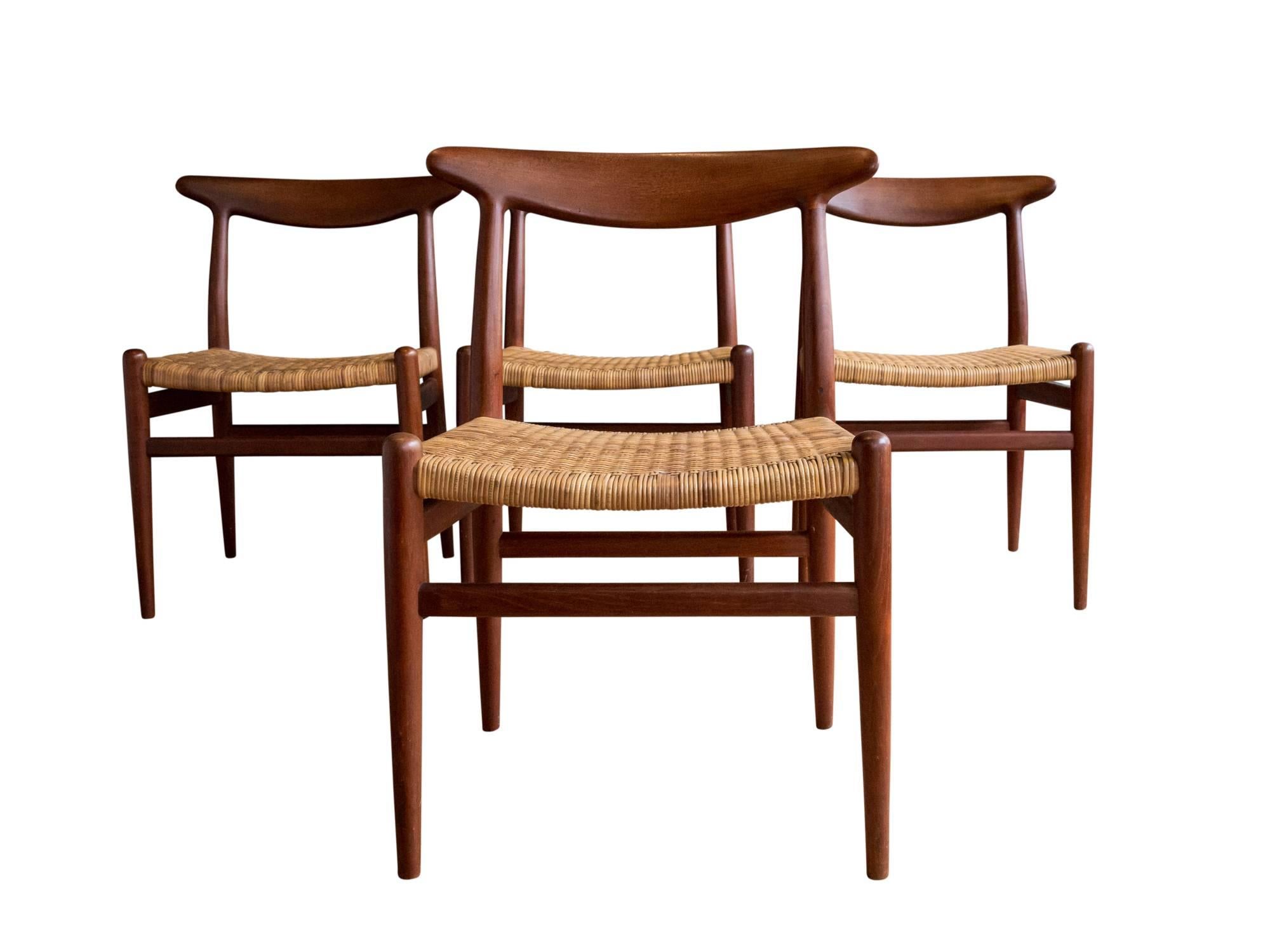 A set of four "W2" dining or side chairs designed by Hans Wegner in 1953. Manufactured by C. M. Madsens Fabriker, circa 1950s. Featuring elegantly carved solid teak frames with curved, tapered back rests. Woven cane seats are in excellent