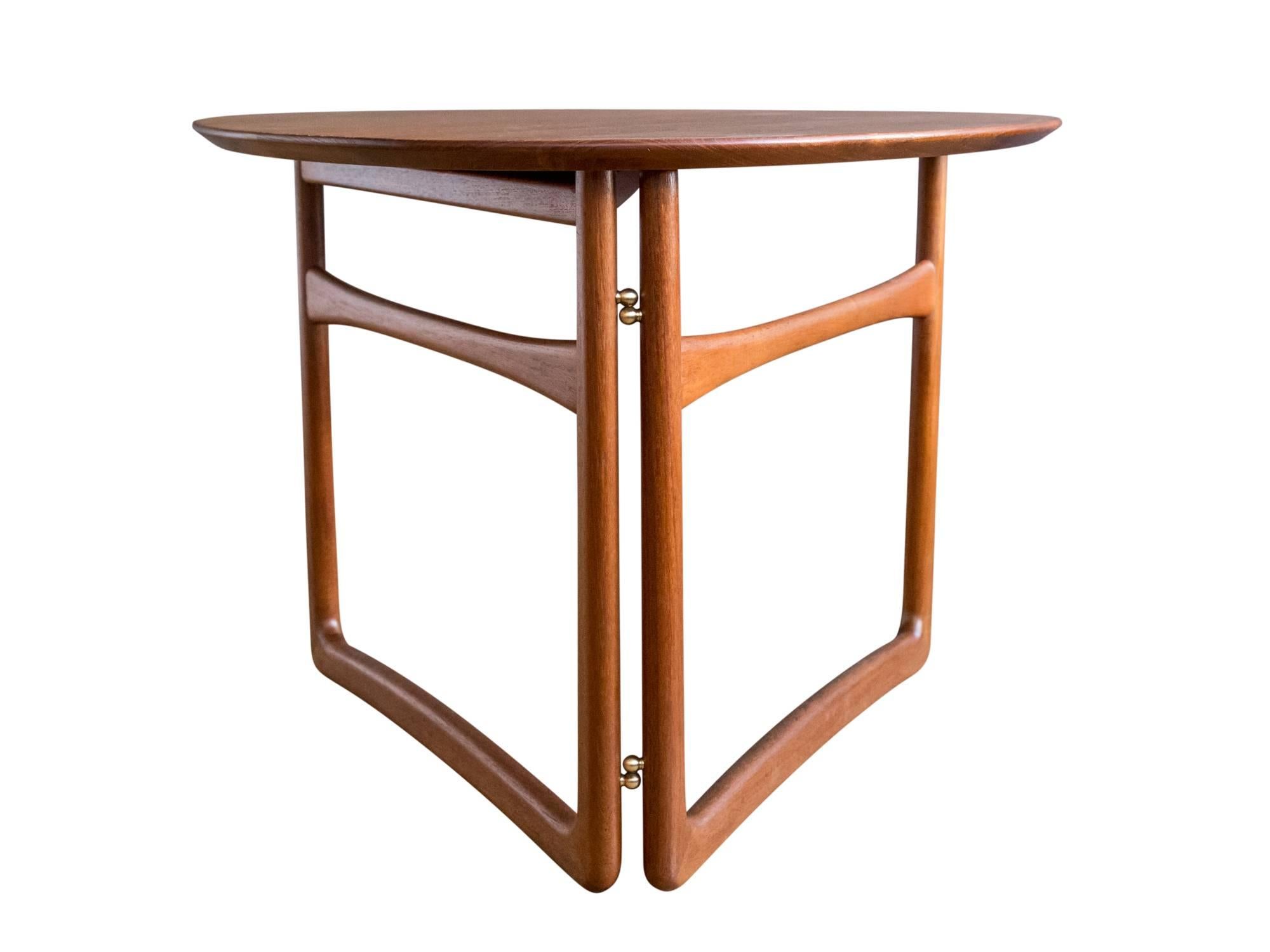 A model FD 18/57 teak folding or side table designed by Peter Hvidt and Orla Mølgaard-Nielsen for France & Daverkosen, circa 1950s. Featuring a triangular teak top with beveled edge and rounded corners supported by a collapsible solid teak sled