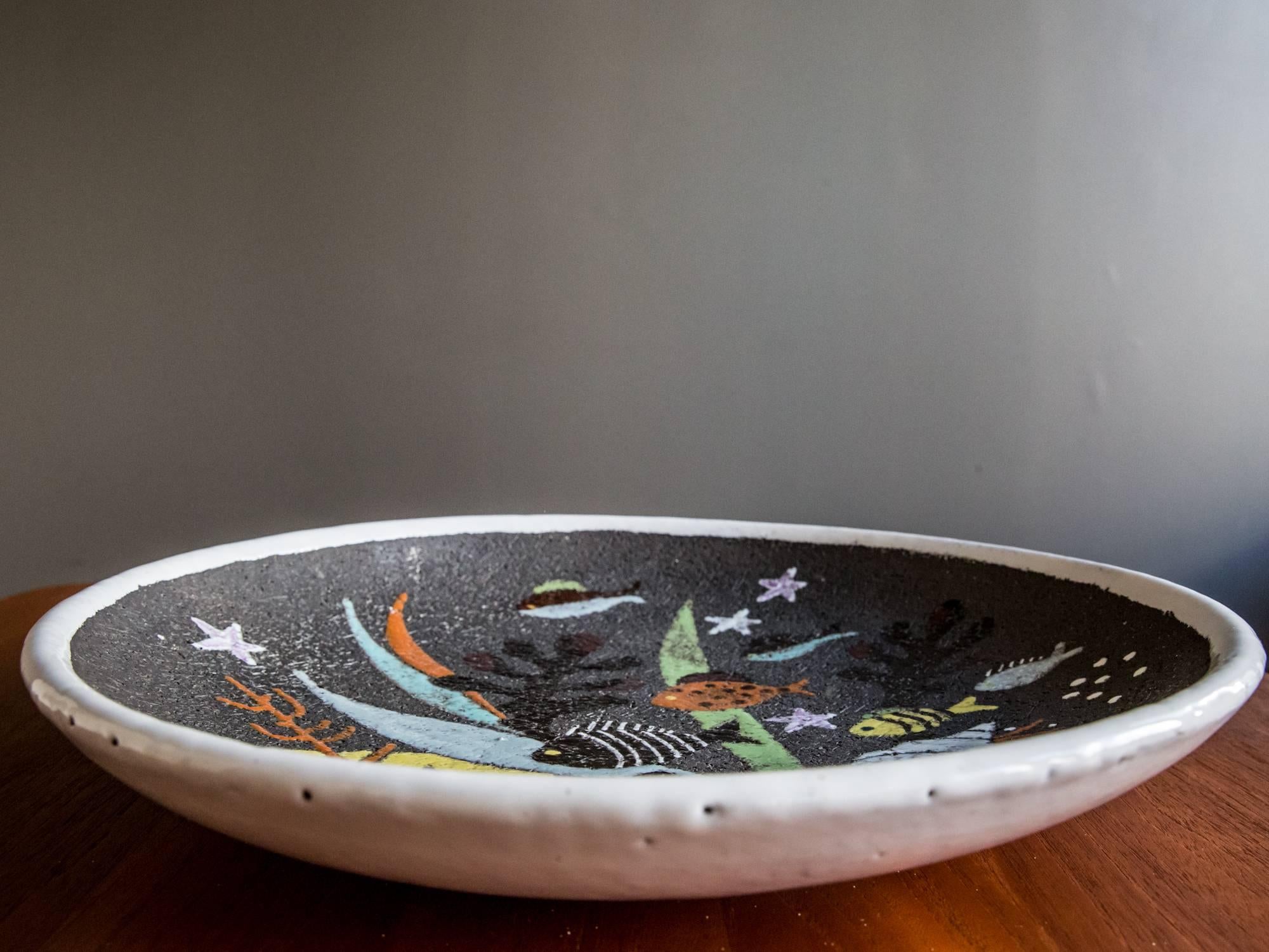 A large ceramic bowl designed by Anna-Lisa Thomson for Upsala Ekeby, circa 1940s or 1950s. Featuring a playful scene of fish and other marine life against a textured background. Bright colors and nice scale make this a great accent piece for a