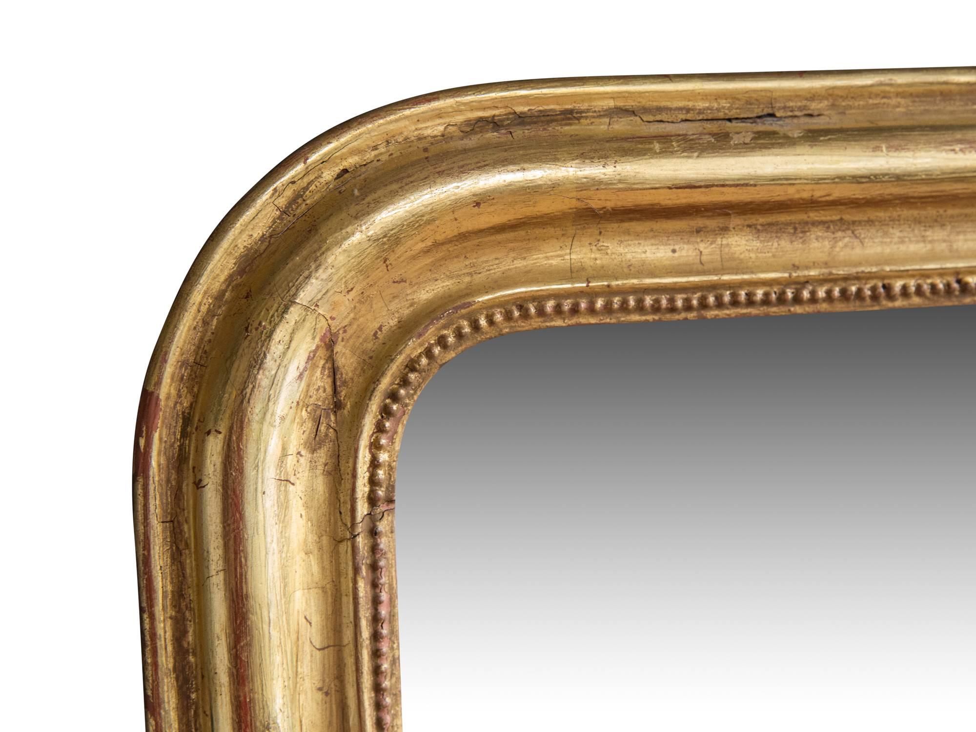 A French Louis Philippe style rectangular wall mirror, ca. 19th century. Featuring a gilt wood frame with soft, rounded edges, interior beaded detail, and typical arched upper corners. Retains antique mercury glass mirror and original wood back. 

A