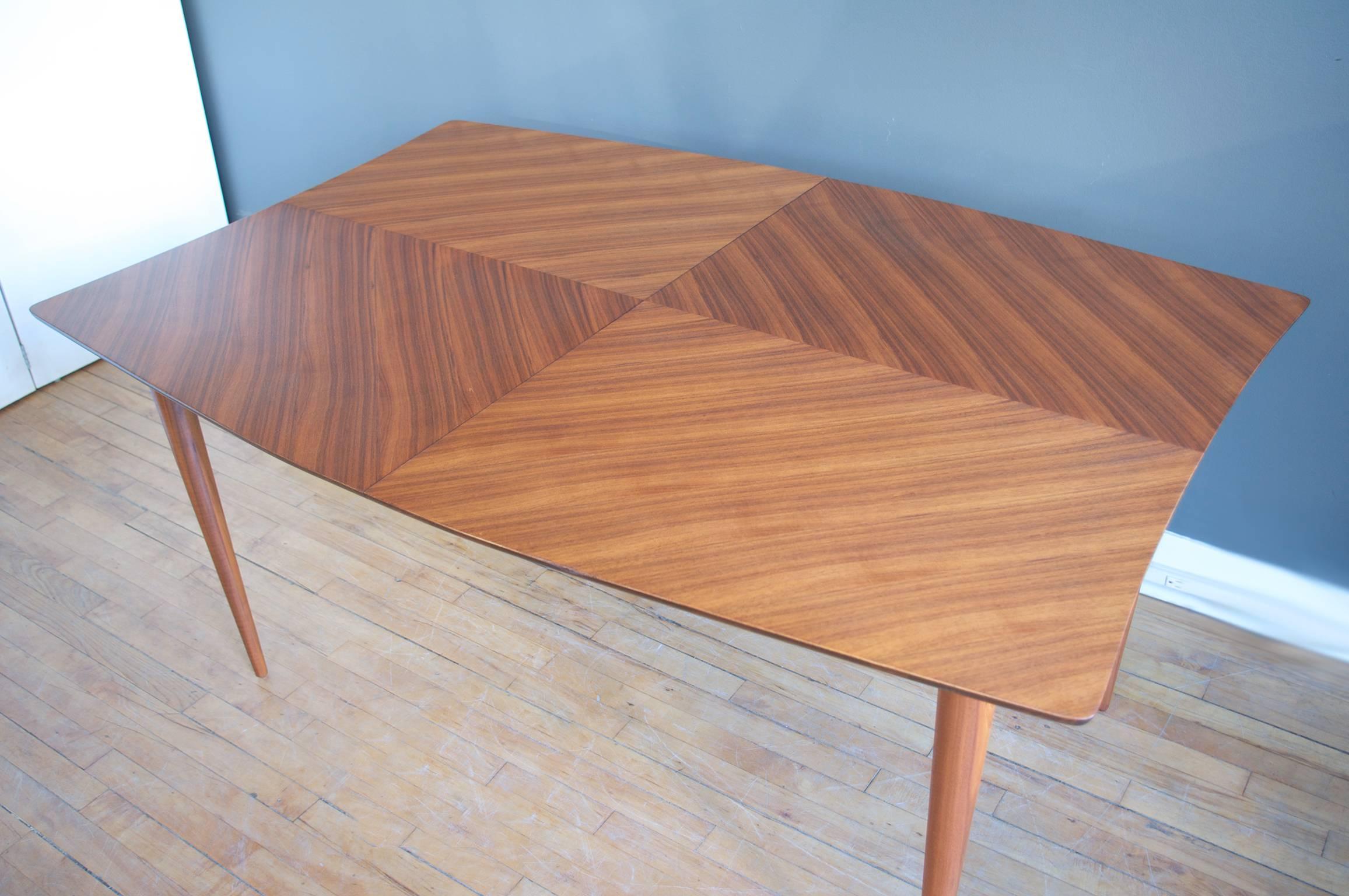 An expandable bleached mahogany dining table designed by Paul Laszlo and manufactured by Brown Saltman of California, circa 1950. Featuring a finely matched top with dramatic graining. Interesting two-tone effect created when leaves are added.