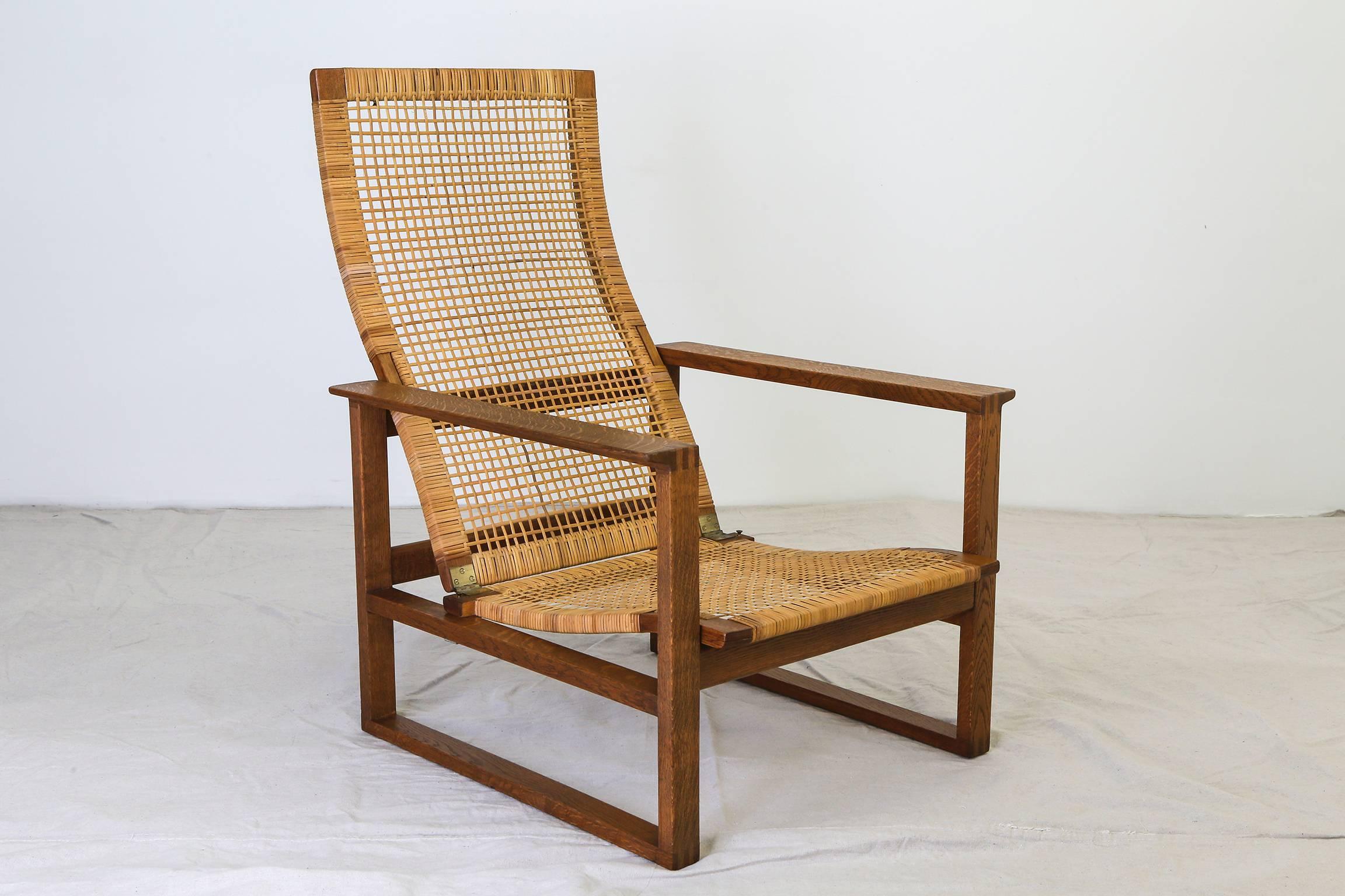A pair of open frame lounge chairs with matching ottomans by Danish designer Børge Mogensen manufactured by Fredericia Stolefabrik, circa 1956. Each set featuring a sled-base chair with oak frame, a caned seat with adjustable caned back, and a