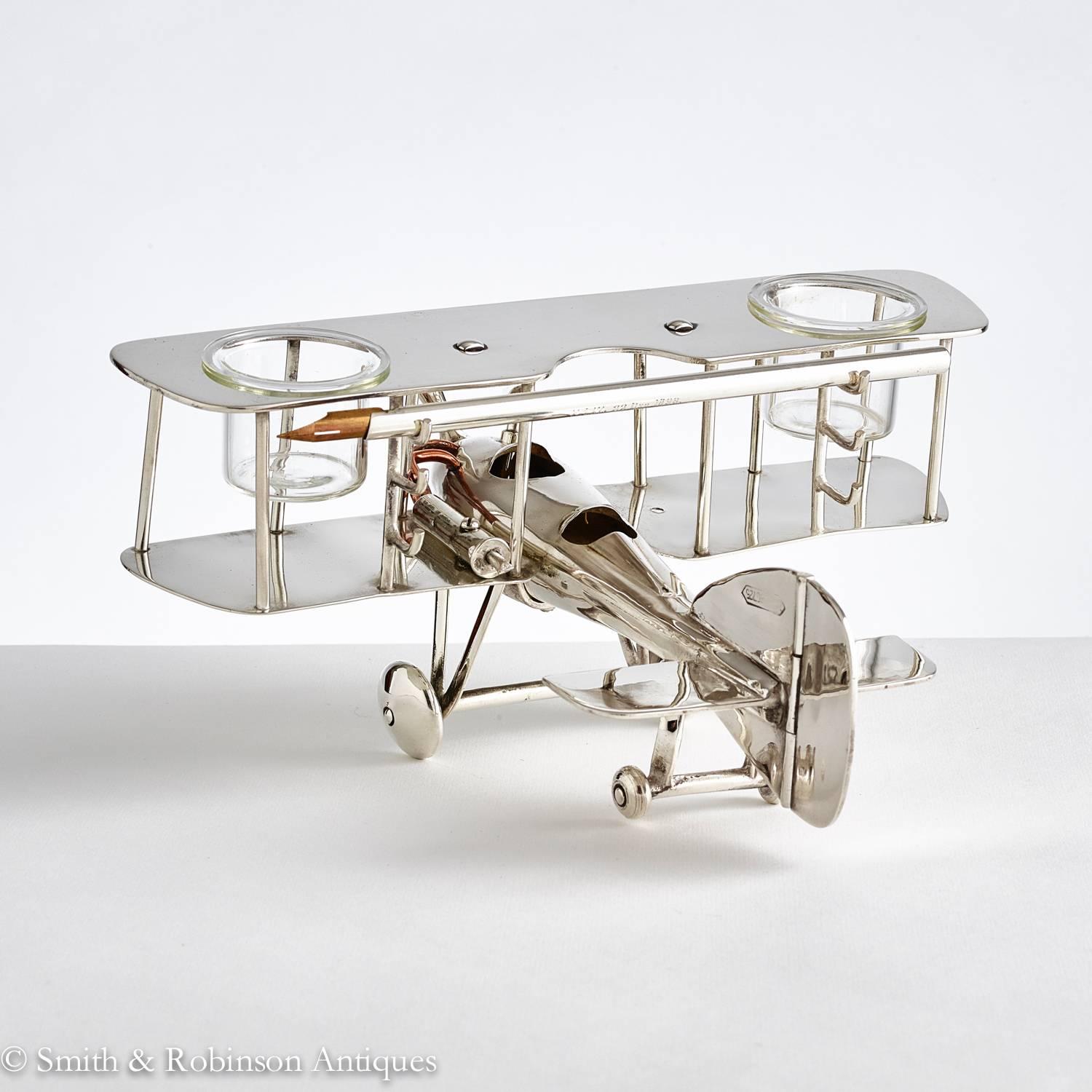 A very unusual desk piece in the form of a WW1 bi-plane, English, circa 1920.
The wings accommodate two glass inkwells. On the reverse of the wings there are three penholders, such as the one shown in the images.
Notably the engine has good
