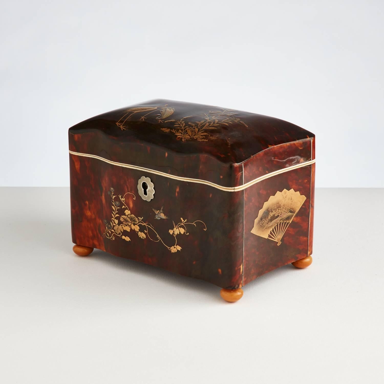 A rare Chinese export tortoiseshell tea caddy made for the Dutch market.
The exterior has decorative lacquer panels on every surface. 
The top and front depict cranes and foliage while the side panels have decorative fans.
The shaped body and