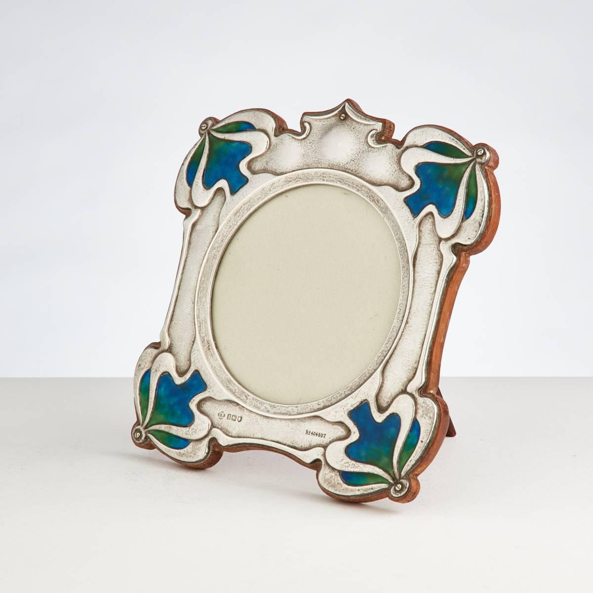A beautiful quality Art Nouveau silver and enamel photograph frame by William Hutton with registration marks and dated London, 1906.
The vibrant enamel is in perfect condition and it retains its original shaped oak back.
The circular opening is 4