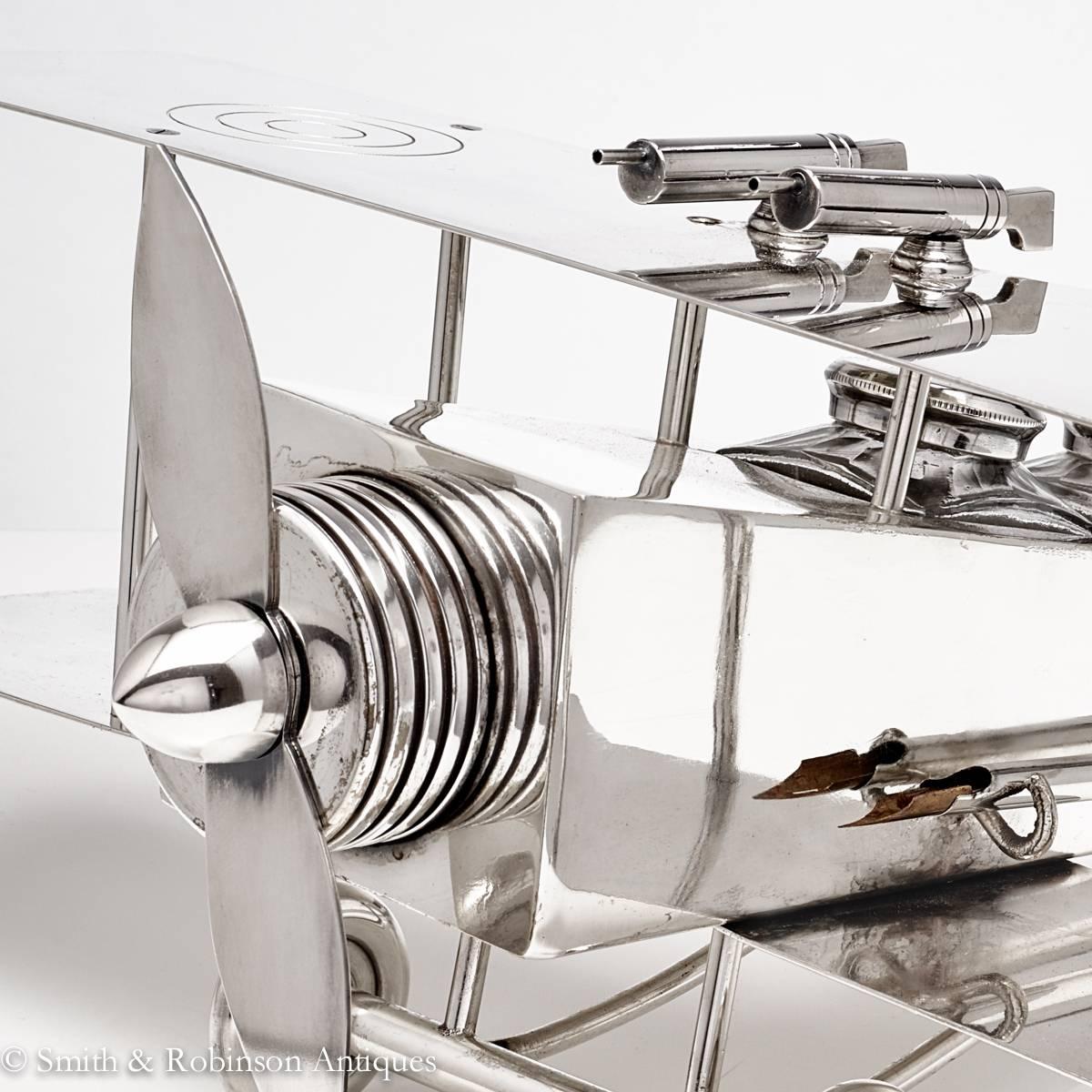 A large and very rare Bi-Plane desk companion piece by makers F. Reichenberg, Germany, circa 1920-1925.

Crafted in silver plated metal, the fuselage 'cockpits' containing a pair of glass and silver-plated inkwells, with dip pen and retaining