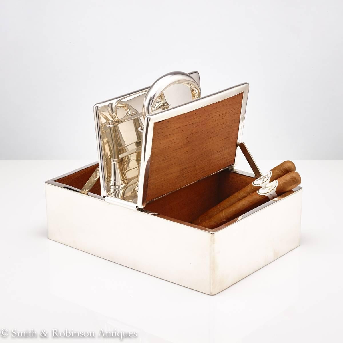 A great automated English silver cigar box, dated London, 1913 by maker Stuart Dawson & Co Ltd.

By pulling the upper part of the central handle the lids move upwards to reveal the two cedar wood interior compartments.
Also the box can be carried
