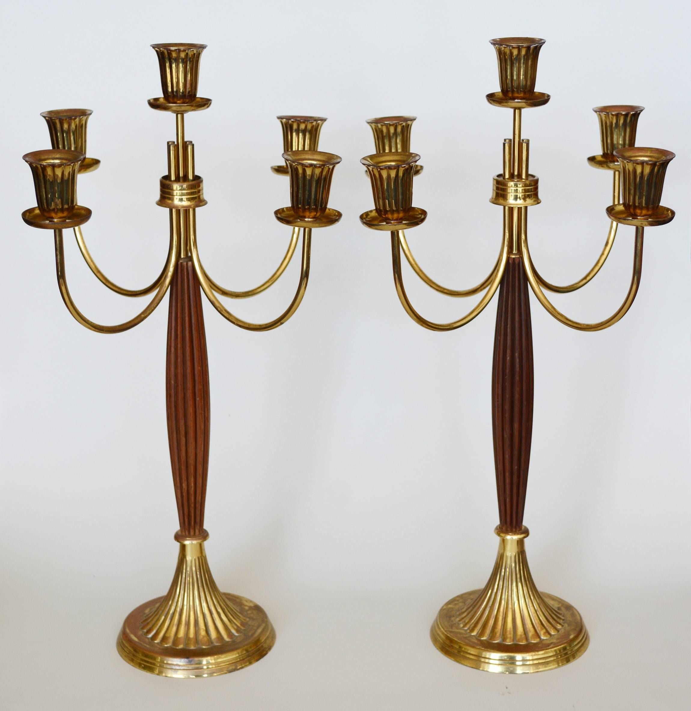 Pair of candelabras made by Dorlyn Silversmith. These each have five brass ribbed holders and a brass ribbed base. The column is ribbed walnut. These are in original condition. There is some light tarnishing. Not all the holders are exactly