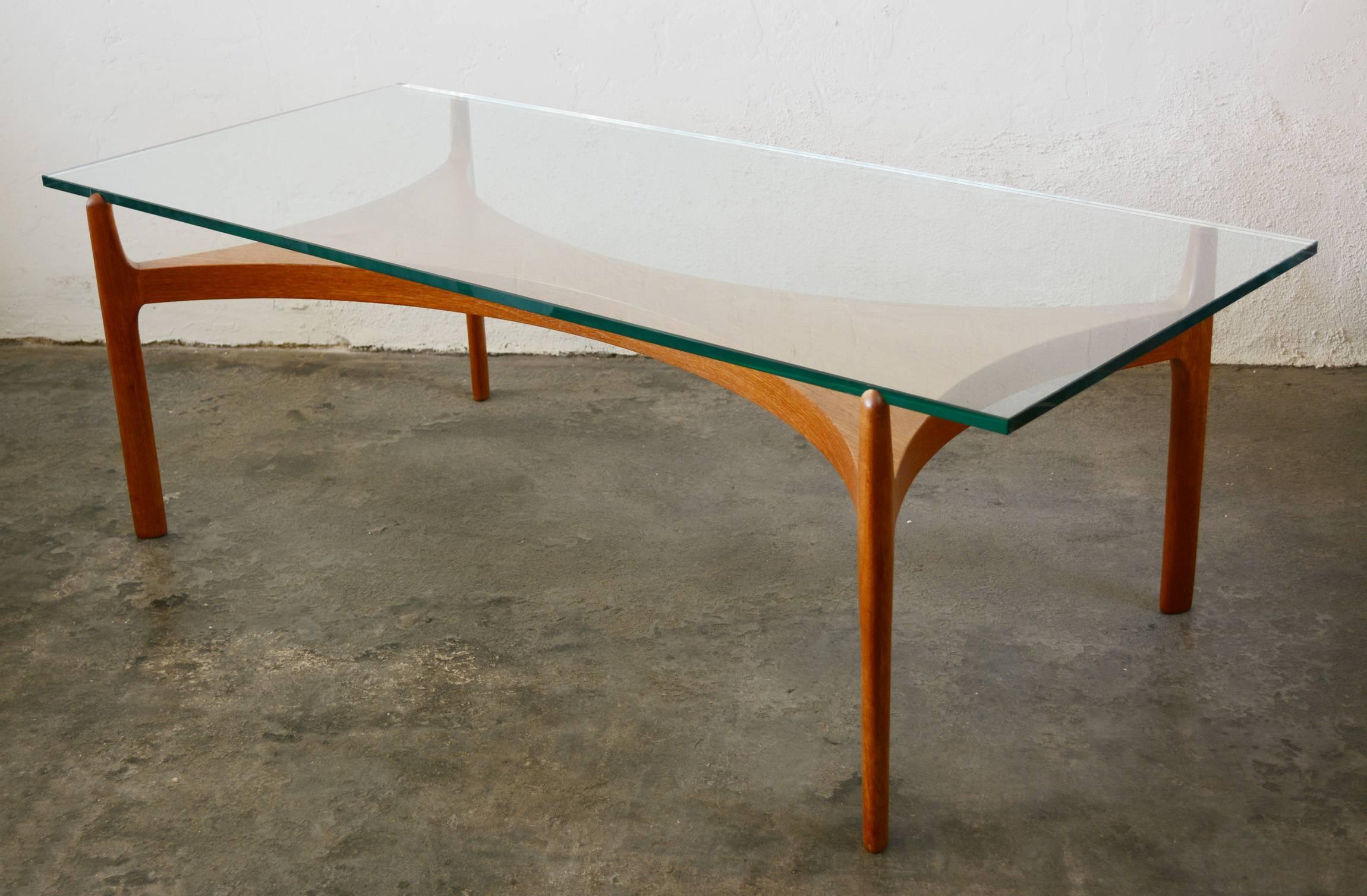 A half inch thick glass floats above a teak base on this table by Sven Ellekaer.
