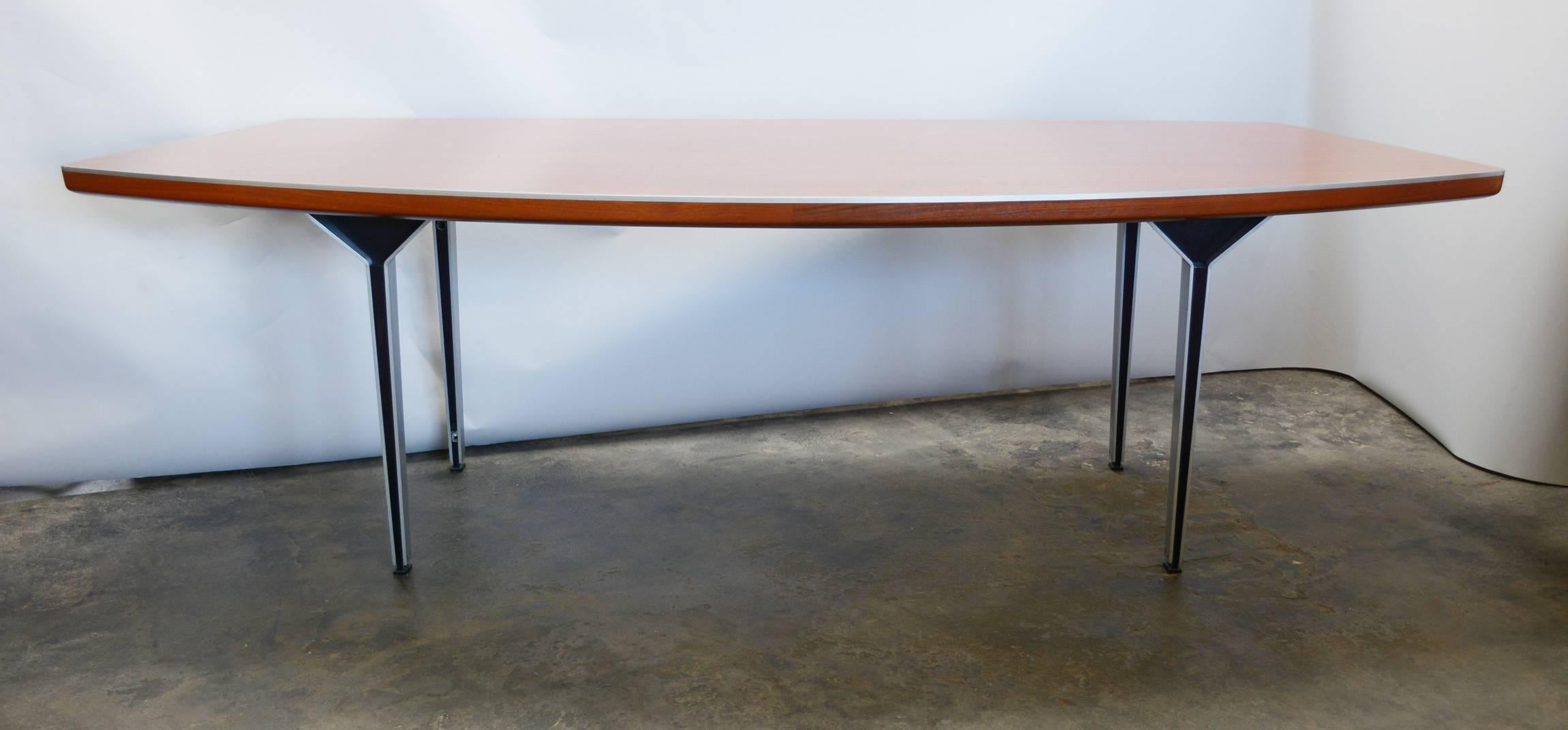 This desk is likely a custom-made piece. The architectural aluminum legs have black anodized aluminum in the center that become the glide at the bottom. There is a band of aluminum around the top edge of the desk. This shows a little wear to the