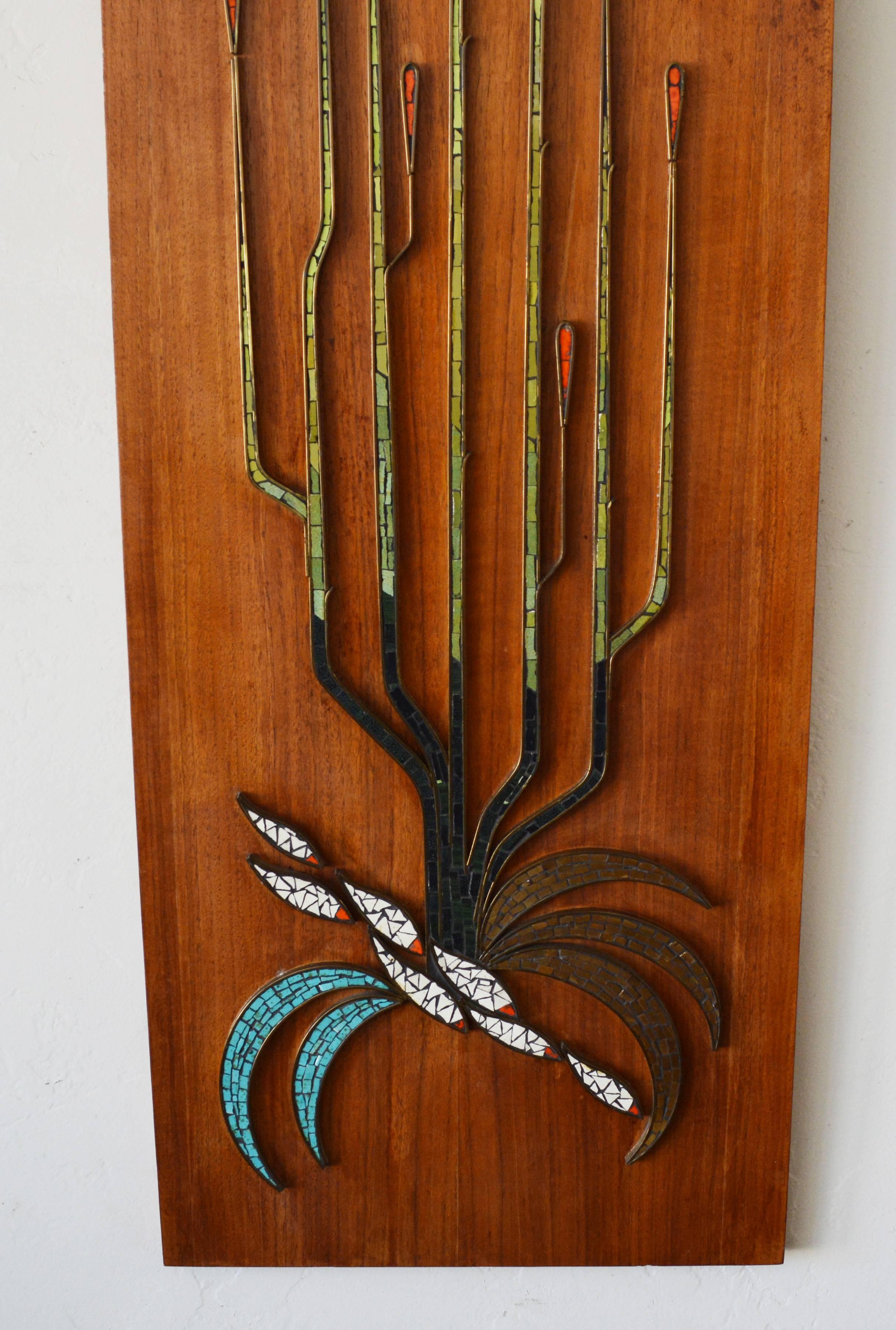 Mid-Century wall hanging mosaic on walnut. The design of a group of fish and seaweed has a patinated brass outline with multi color glass tiles in the interior. This is a very well executed piece of high quality.