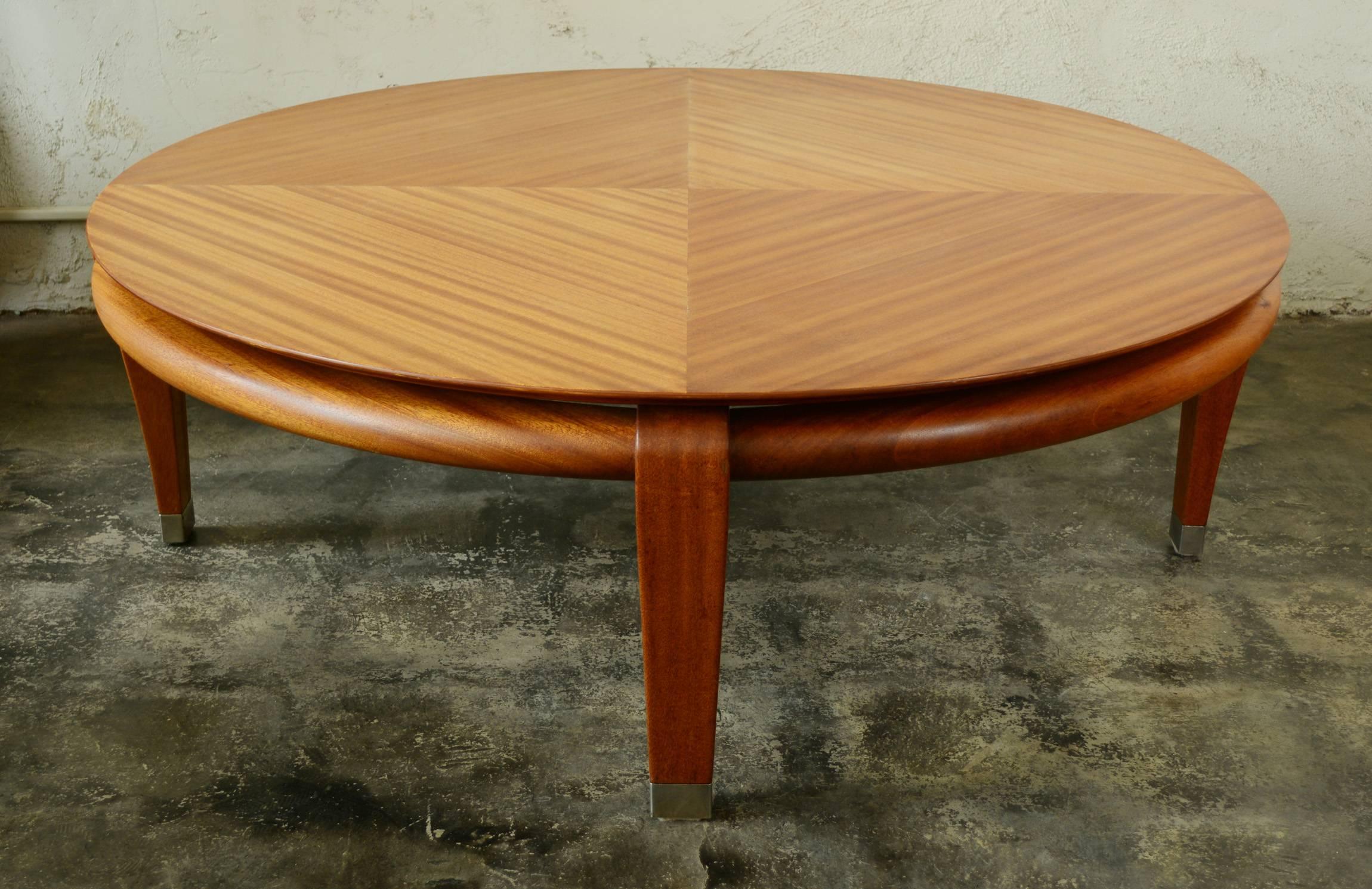 Exquisitely shaped mahogany coffee table designed by Paul Laszlo. The top floats on the base. The legs have nickel plated sabots. The designer utilized the light and dark bands of the mahogany to create a visually attractive pattern on the top. This