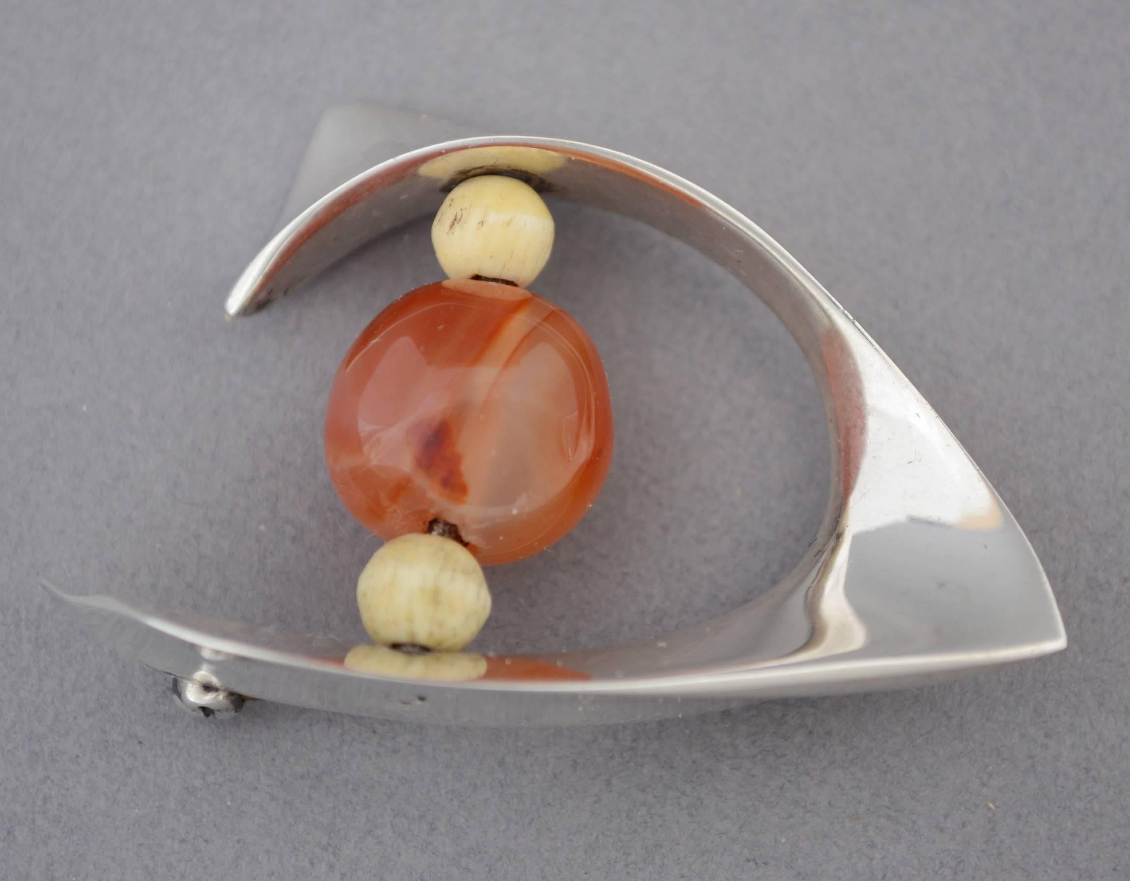 Modernist pin by Ronald Pearson. This pin is sterling with a large carnelian agate bead with a small bone bead on either side.