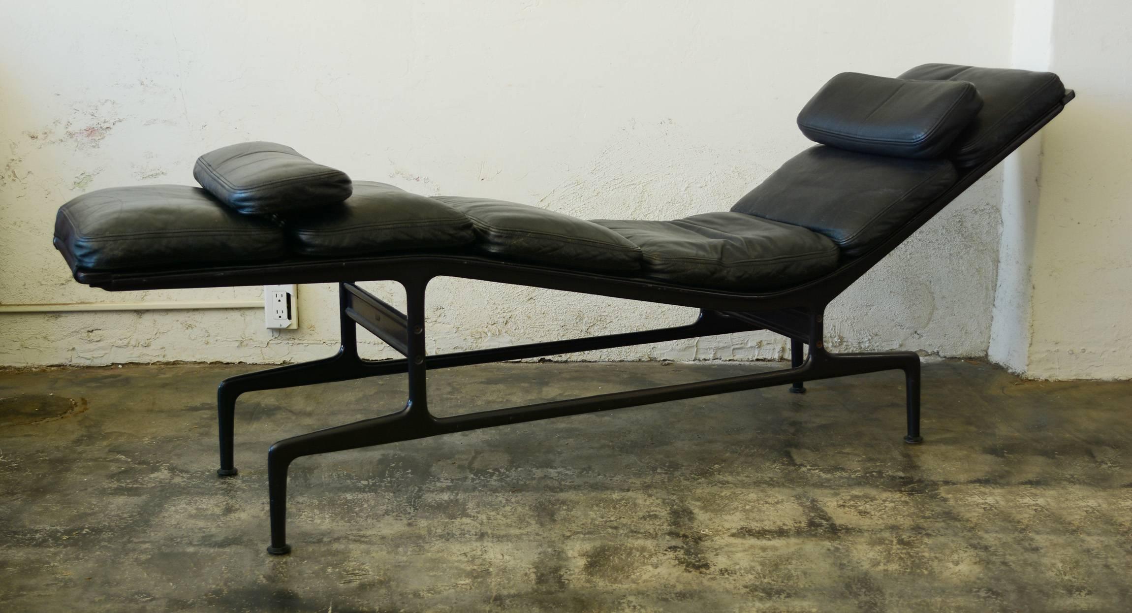 Aluminum and leather chaise lounge designed by Charles and Ray Eames. This has an eggplant frame and black leather. The leather has a nice patina. The frame has some losses to the paint on one side. 