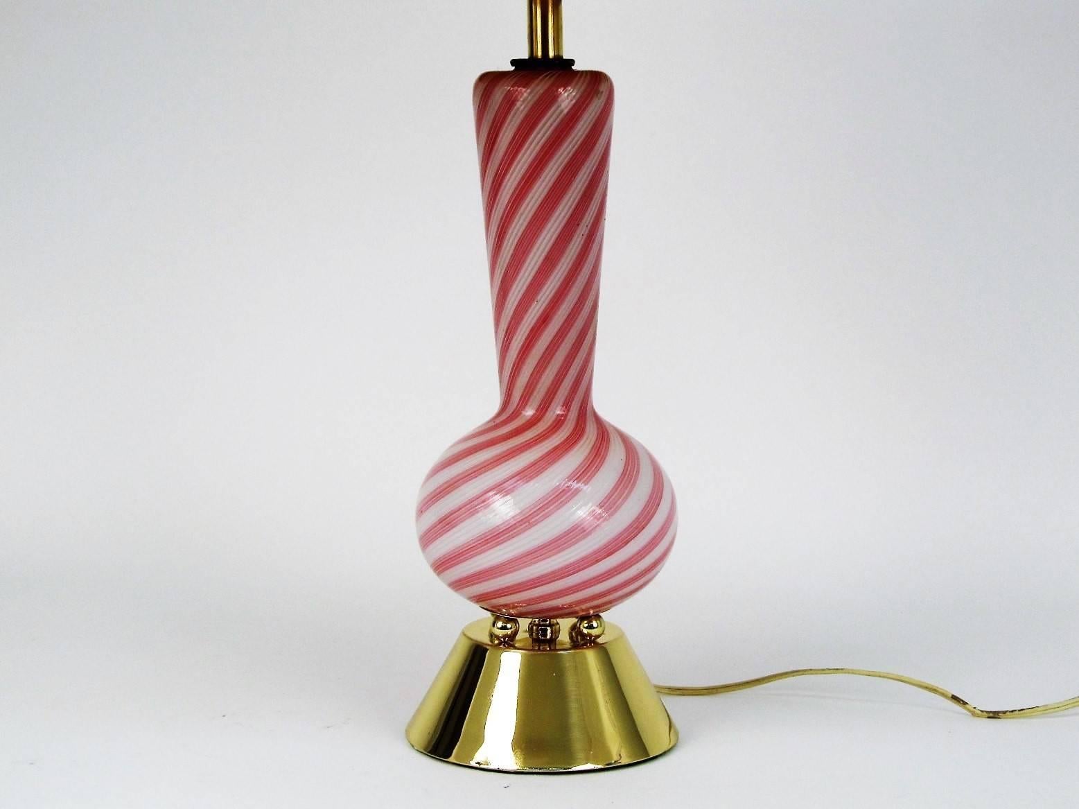 Pretty in pink, this lovely Murano glass lamp displays the exacting craftsmanship that Murano glass is world famous for. Precise alternating pink and white canes of glass swirled and shaped into a beautiful table lamp. 

Shade is not original, and