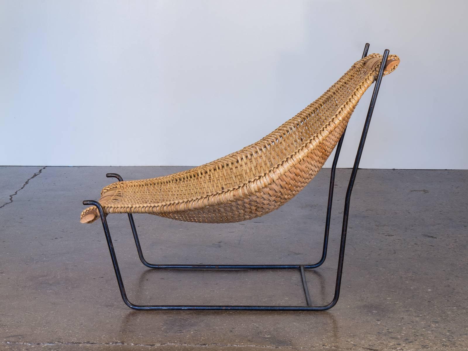 Danny Ho Fong's unique design for Tropi-cal dates to the late 1950s or early 1960s and is a delightful mélange of traditional weaving Craft and modern design. An iron frame supports a woven sling finished with a beautiful braided edge. The chair is