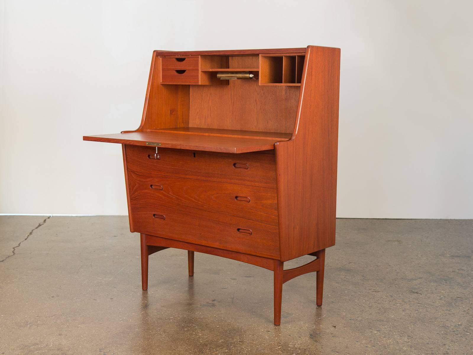 Beautiful Danish modern cabinet designed by Arne Wahl Iversen in the 1960s. A key opens the desk top, which flips down to reveal mini drawers, letter organizers and a built-in light. Add a mirror and this piece could work as a vanity, too. Three