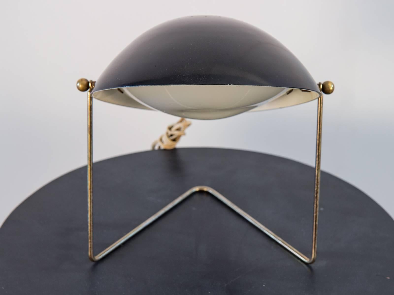 Lamp designed by Gerald Thurston for Lightolier in the 1950s. The black shade tilts and the lamps can also be hung on the wall as a sconce. A diffuser keeps the light gentle. Black painted metal shade and brass frame. In very good vintage