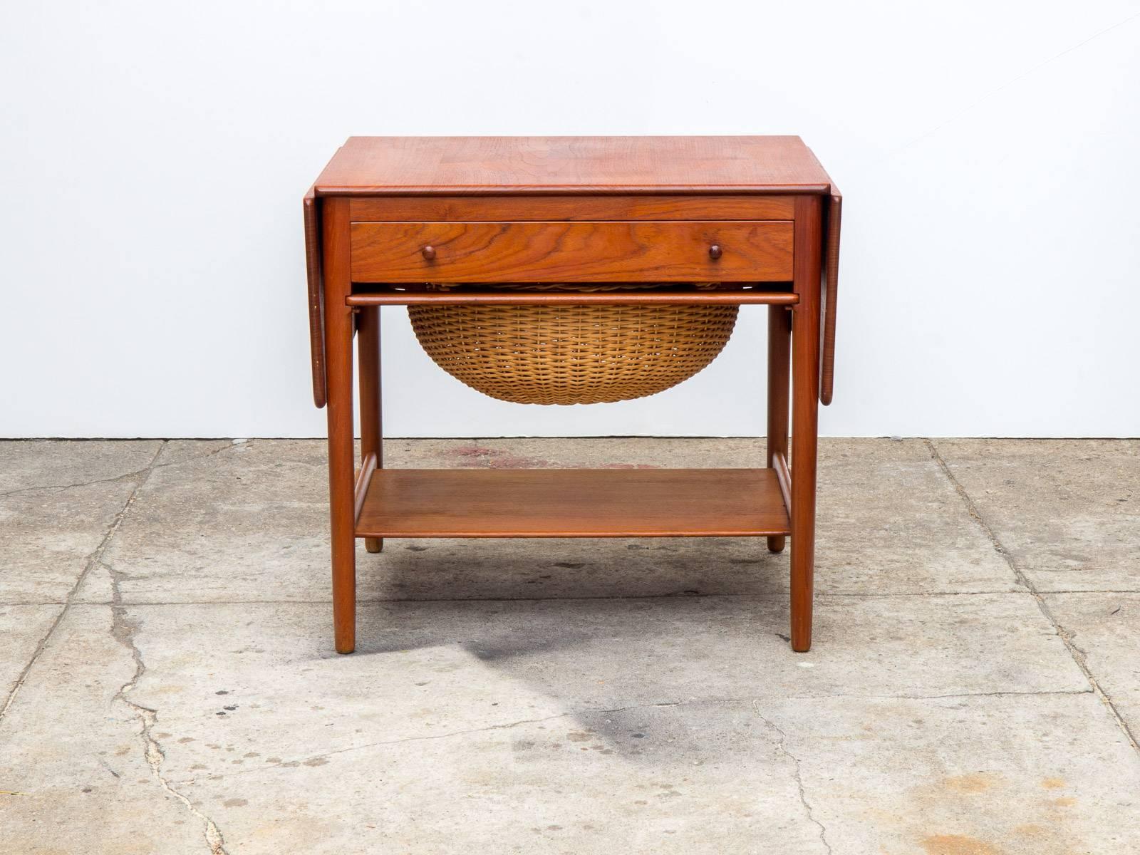The AT-33 is a marvelous example of Hans J. Wegner design and Andreas Tuck craftsmanship, this sewing table features drop leaves, a beautiful wicker basket and deep oak drawer with spindles and divisions for thread and other supplies. This is an
