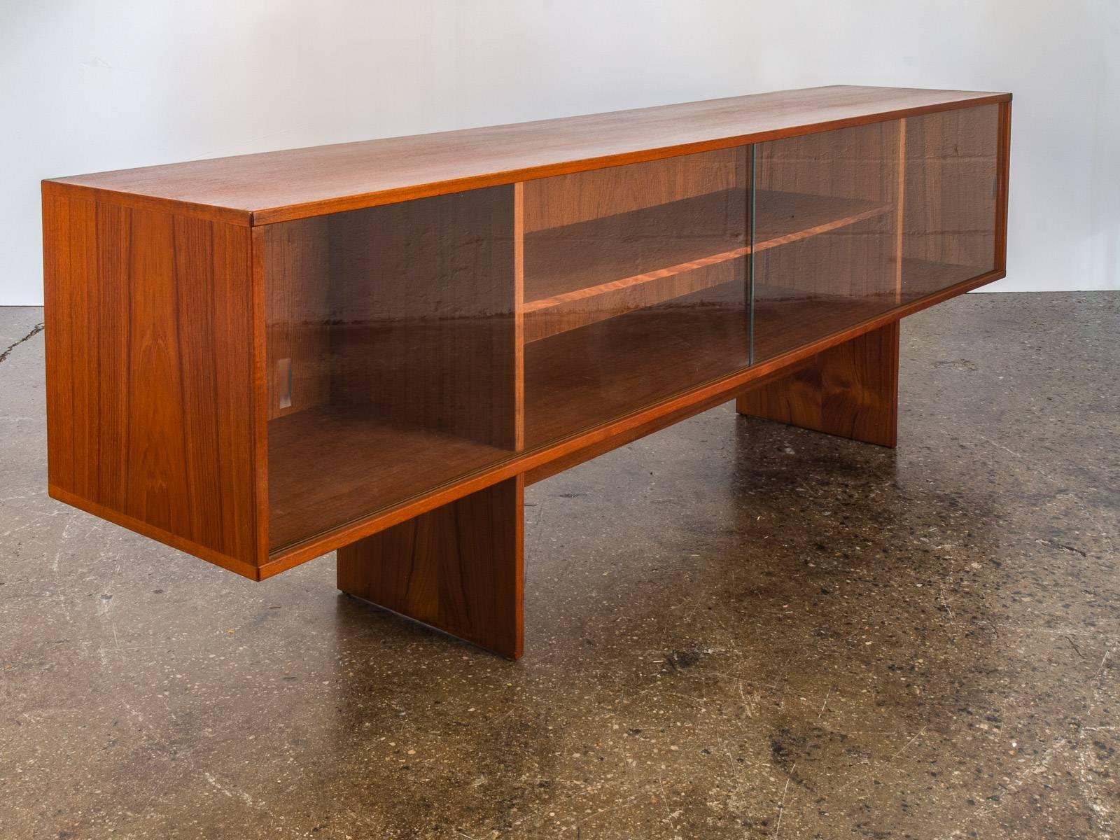 Jens Quistgaard media credenza for Peter Lovig by Dansk is a lovely sliding glass door unit crafted in teak. This piece is in excellent vintage condition with a lovely patina with age-appropriate wear. The wood selection is exquisite, with a
