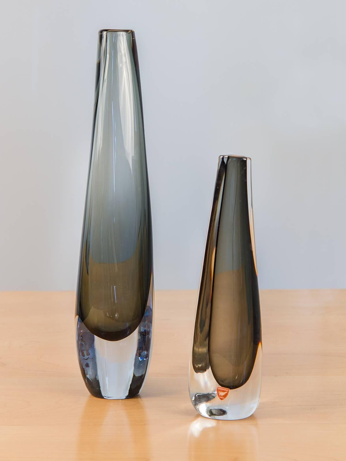 Two elegantly tall, handblown glass vases designed by Nils Landberg in 1956 for Orrefors. A delicate, sultry example of Scandinavian modern table top elements. Hand etched signage on the underside.

Smaller vase measures 2
