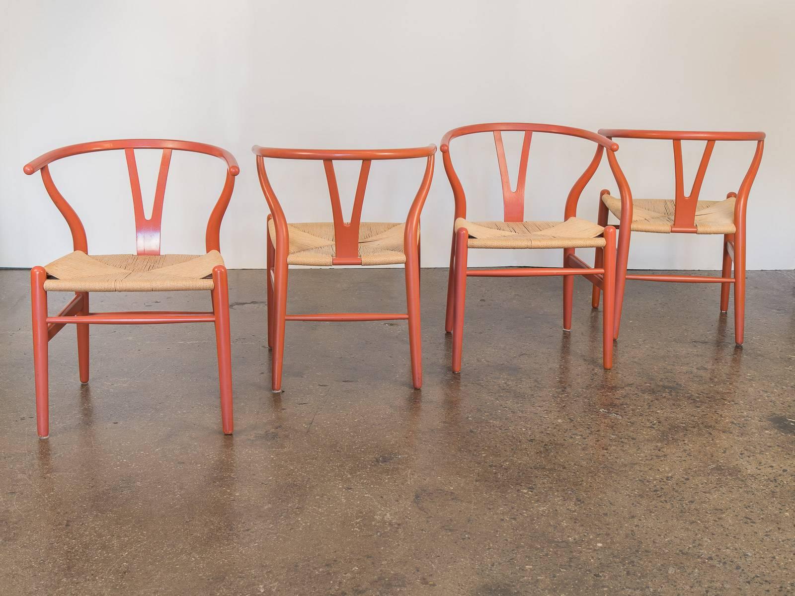 Set of four Hans J. Wegner Wishbone Chairs for Carl Hansen & Son. First designed in 1949, these four wishbone chairs—also known as the CH24 chairs—retain their original salmon color finish. The wishbone “Y” shaped backing and rounded arm rests