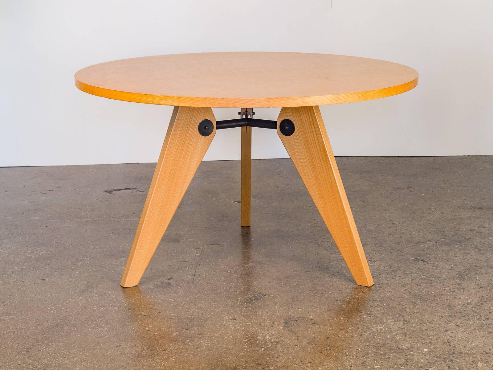 Stunning Jean Prouvé Gueridon Table for Vitra from 2002. This round 47-inch wide, 1.75 thick, oak veneer tabletop is supported by a black steel, tripod brace. Three diagonally cut legs are fixed to the base for equal weight distribution. This
