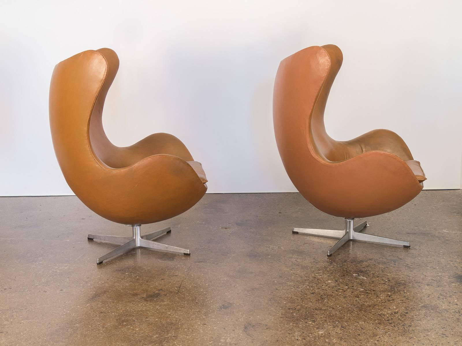 An exceptional pair of vintage cognac leather Egg chairs by Arne Jacobsen for Fritz Hansen. Sculpted backs command attention while also cradling the body comfortably within it’s curvilinear form. From the early 1960s, the 25 year leather is soft and