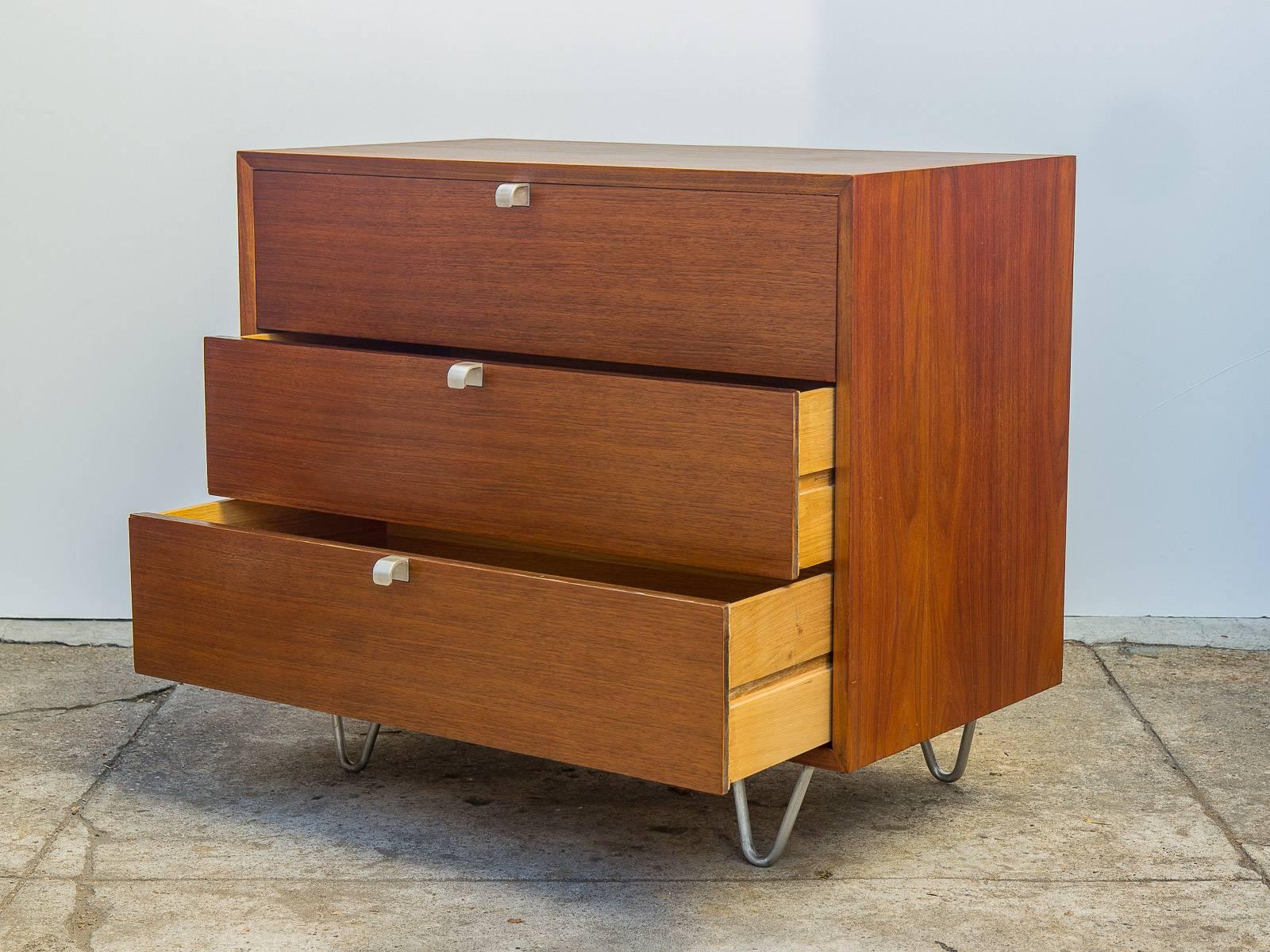 Three-drawer walnut dresser by George Nelson for Herman Miller. Staunch dresser dates from the 1950s and has been professionally restored. Aluminum J-pull handles and hairpin legs accent the modestly sized walnut body. Top drawer features three