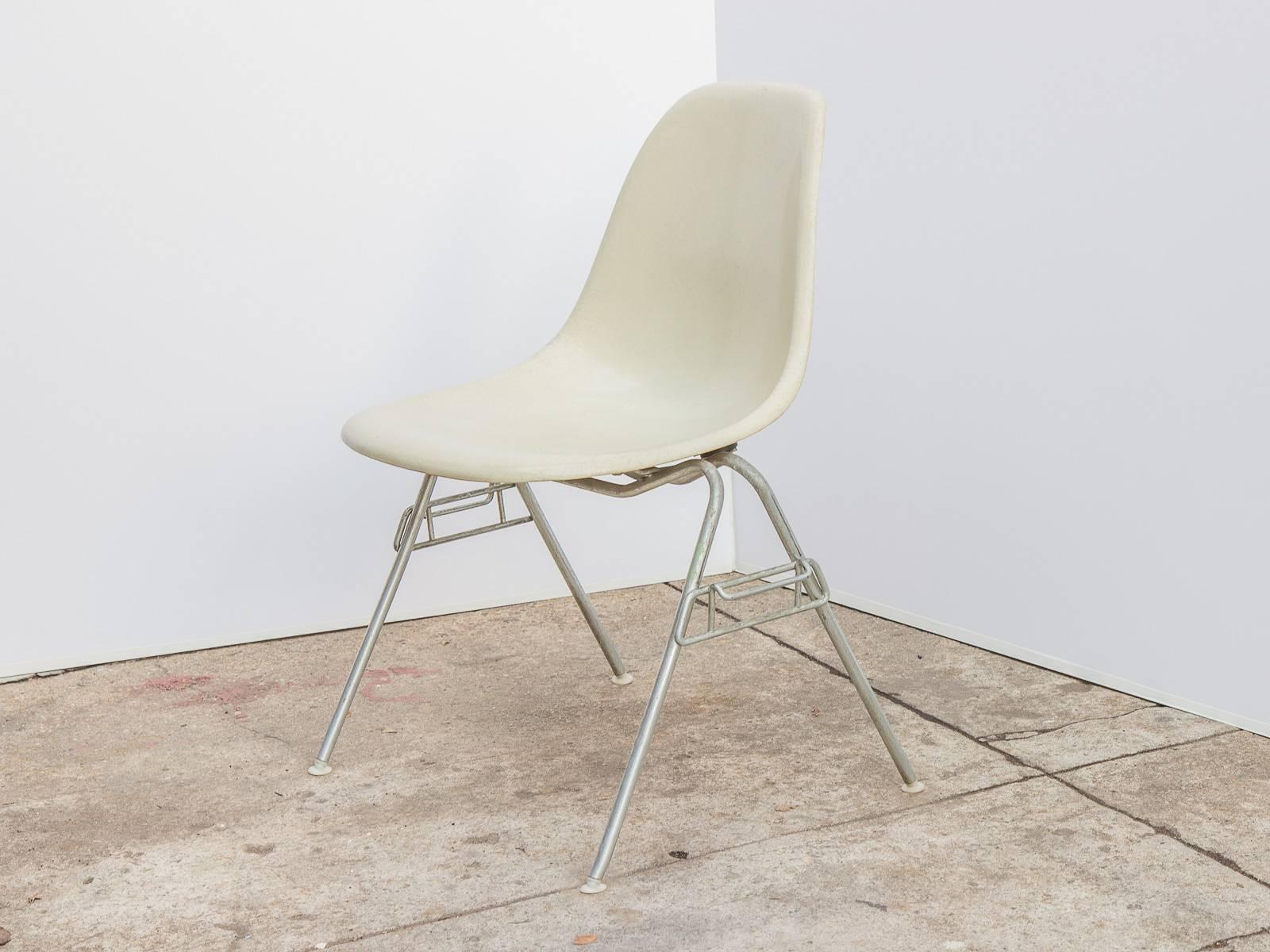 Original 1960s molded fiberglass parchment white shell chairs on stacking base, designed by Charles and Ray Eames for Herman Miller. Gleaming shells are in original condition, each with a distinct thready texture.  Shown here mounted on stacking