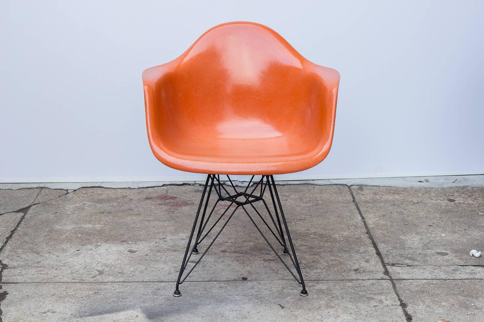 Classic Charles and Ray Eames molded fiberglass armchair in orange on the black Eiffel base for Herman Miller. We have three of these available. Original finish with distinct thread texture. Herman Miller stamp on the underside. Other colors and