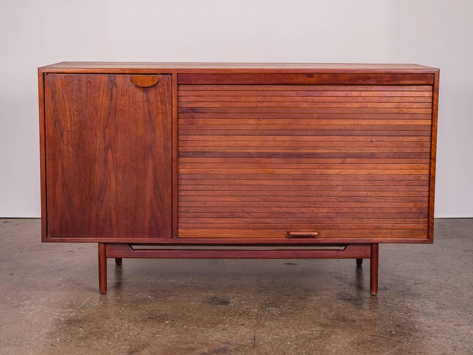 Late 1960s walnut tambour door credenza by Jens Risom. Sturdy bodied, mid-sized credenza has been fully restored and retains its gleaming period-specific patina. The two storage areas have adjustable shelving inside, and are adorned with the