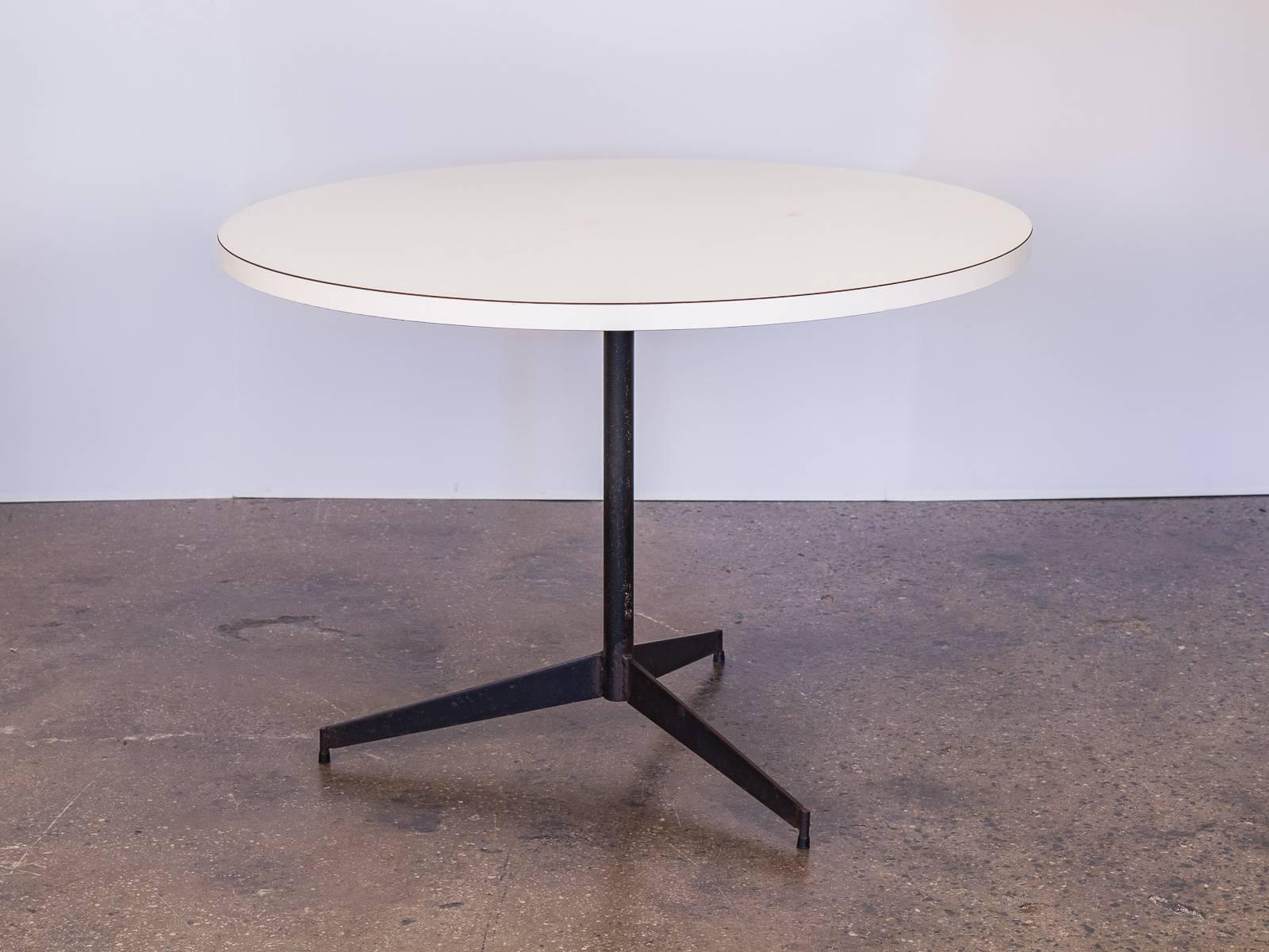 1960s white Formica round dinette table on black pedestal steel base. Fits up to four people. Lovely for a breakfast nook or communal office kitchen space. While this dining table has been lovingly used, it is in very good condition the white