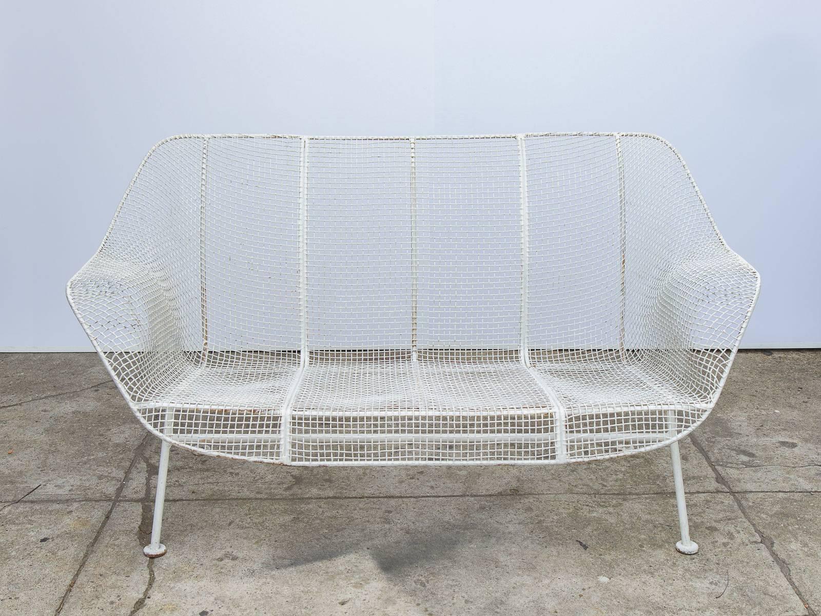 White welded Russell Woodard settee, from the Sculpture line. Iron mesh follows the winged armrests and low slung seat to form this timeless design. Our example is a vintage, 1960s settee that has some age-appropriate wear to the powder-coated mesh,