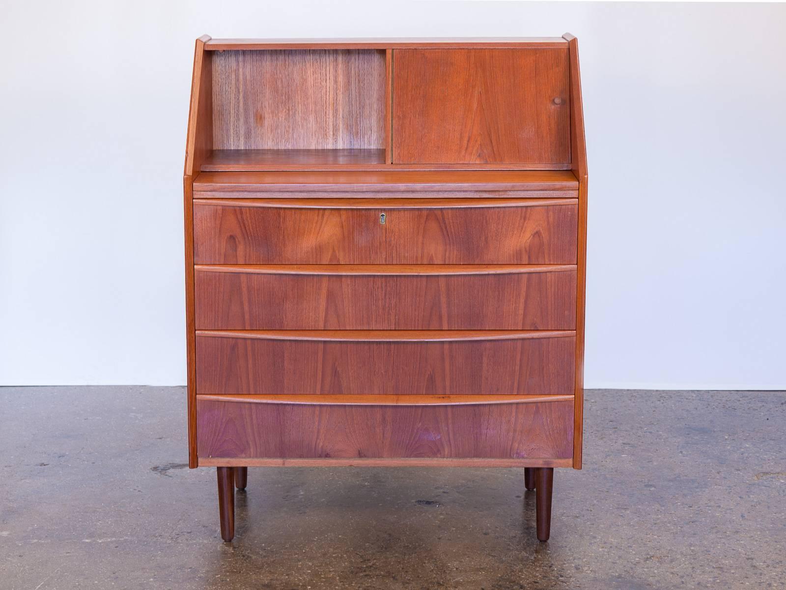 Scandinavian teak secretary. Gorgeous teak wood selection is rich and bright. Top right side opens to reveal a mirror and a reflective shelf for small storage. Four dresser drawers along with a desk surface when top is pulled out. A petite-sized