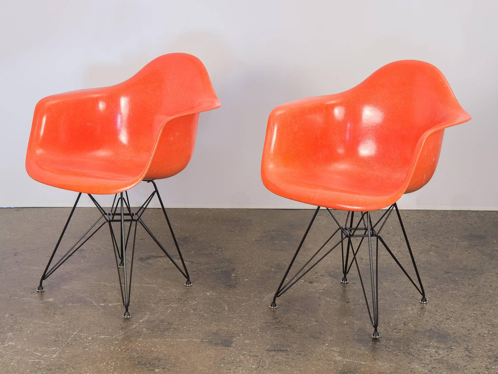 Pair of Classic Charles and Ray Eames 1960s molded fiberglass armchairs in orange on a reissued black Eiffel base for Herman Miller. Original finish with distinct thread texture, in excellent condition with clean edges. Herman Miller stamp on the