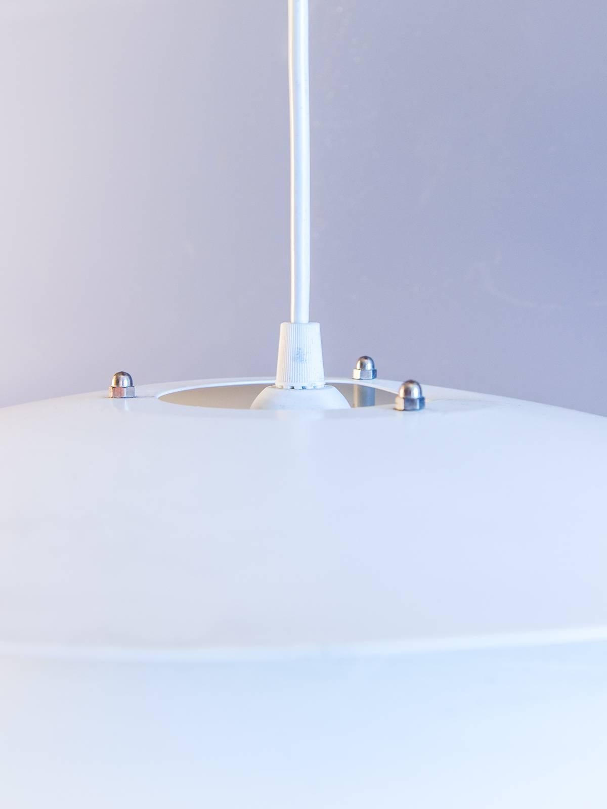 Vintage 1960s Scandinavian modern light fixture. Concentric reflectors create a sleek futuristic design, reminiscent of lighting by Poul Henningsen. White enameled aluminium is in very good condition. Slight bend in the very top reflector visible