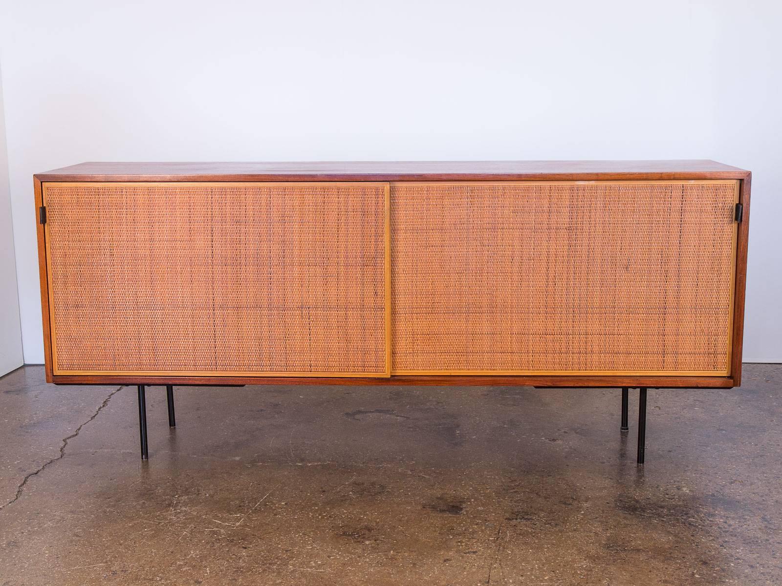 Scarce example of Florence Knoll’s walnut and woven cane door credenza. As seen in the Knoll Associates catalogue published in 1950, model 116. This early design adorns a gorgeous, natural walnut wood selection and features four sections with seven