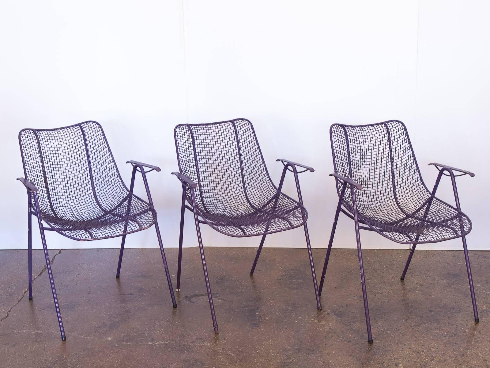 Set of six purple outdoor iron mesh armchairs by Russell Woodard. These stylish Industrial modern, weather resistant patio chairs stack on top of each other for easy storing. Each chair has varying degrees of age-appropriate wear, leaving a charming