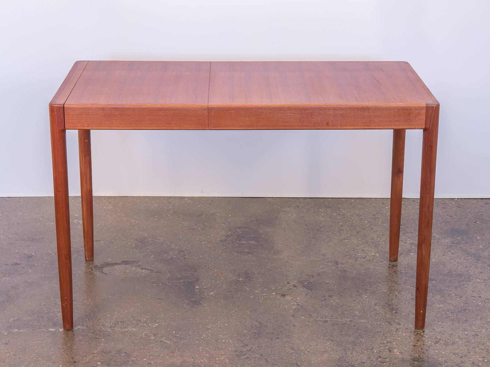 Lovely, compact Danish Modern table with leaf. This gleaming 1960s teak table has been polished, oiled, and cleaned and has a brilliant presence. Surface has some age-appropriate wear, overall in very good vintage condition. Removable leaf allows