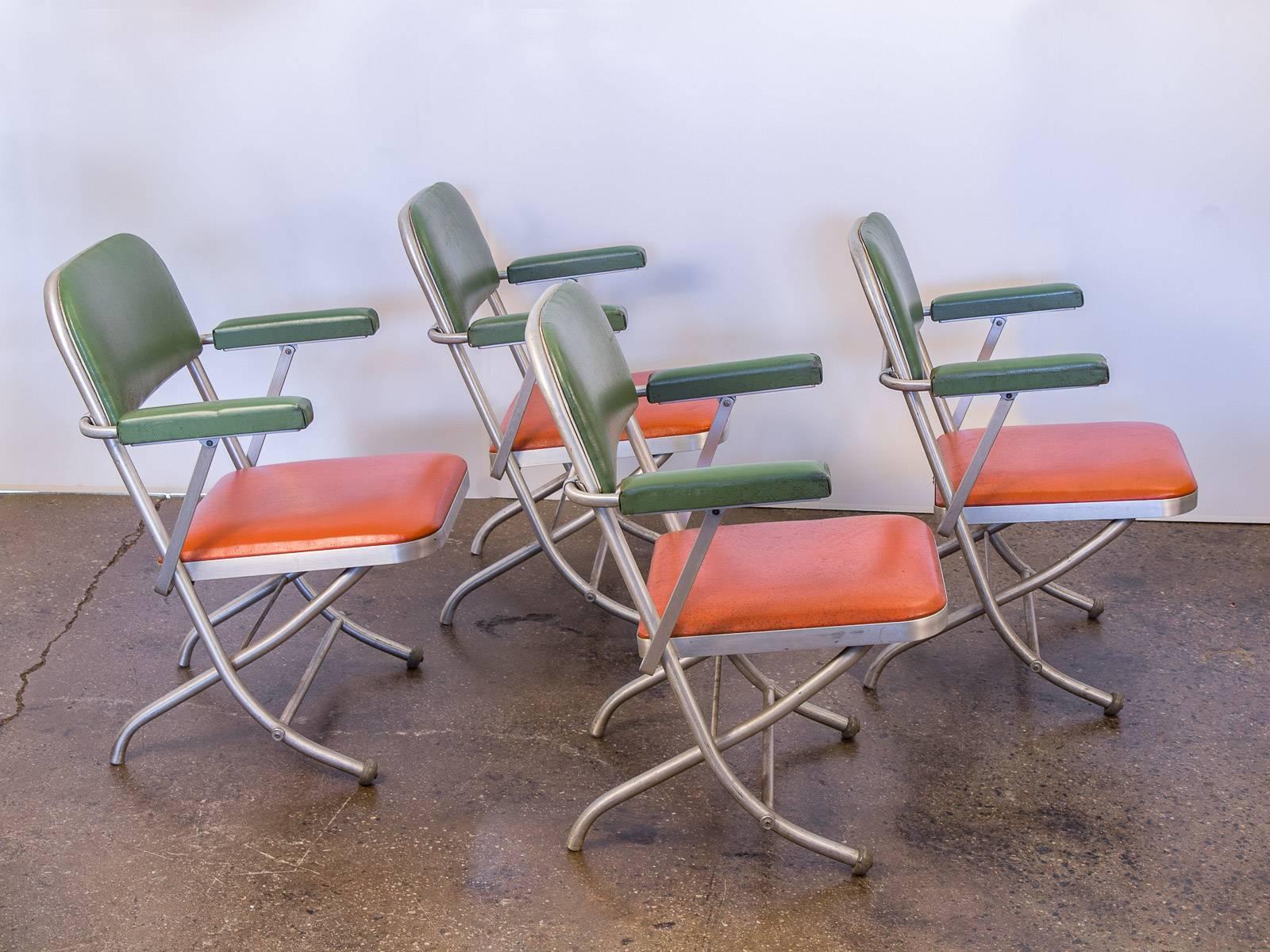 Set of four, 1940s, Warren McArthur two-tone folding armchairs for Mayfair Industries. In excellent vintage condition. Tubular, brushed aluminum frames are sculptural and fold with ease, while the subdued orange and green cushions are robust and