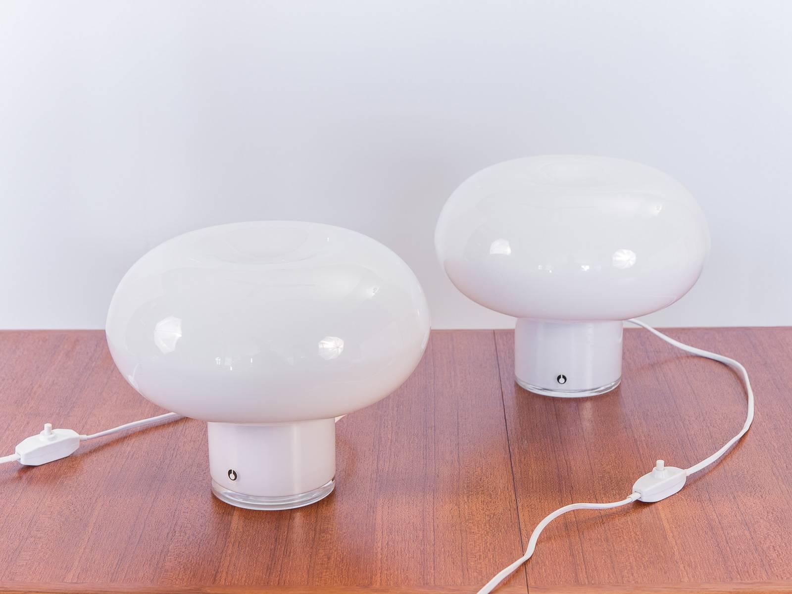 Scarce pair of minimal, white glass table lamps for Pukeberg, Sweden. The spherical, ellipsoid shade sits on top of the glass stem for a low, attractive profile. Glass is very clean with no visible scratches. Adorn your sideboard or bedside with