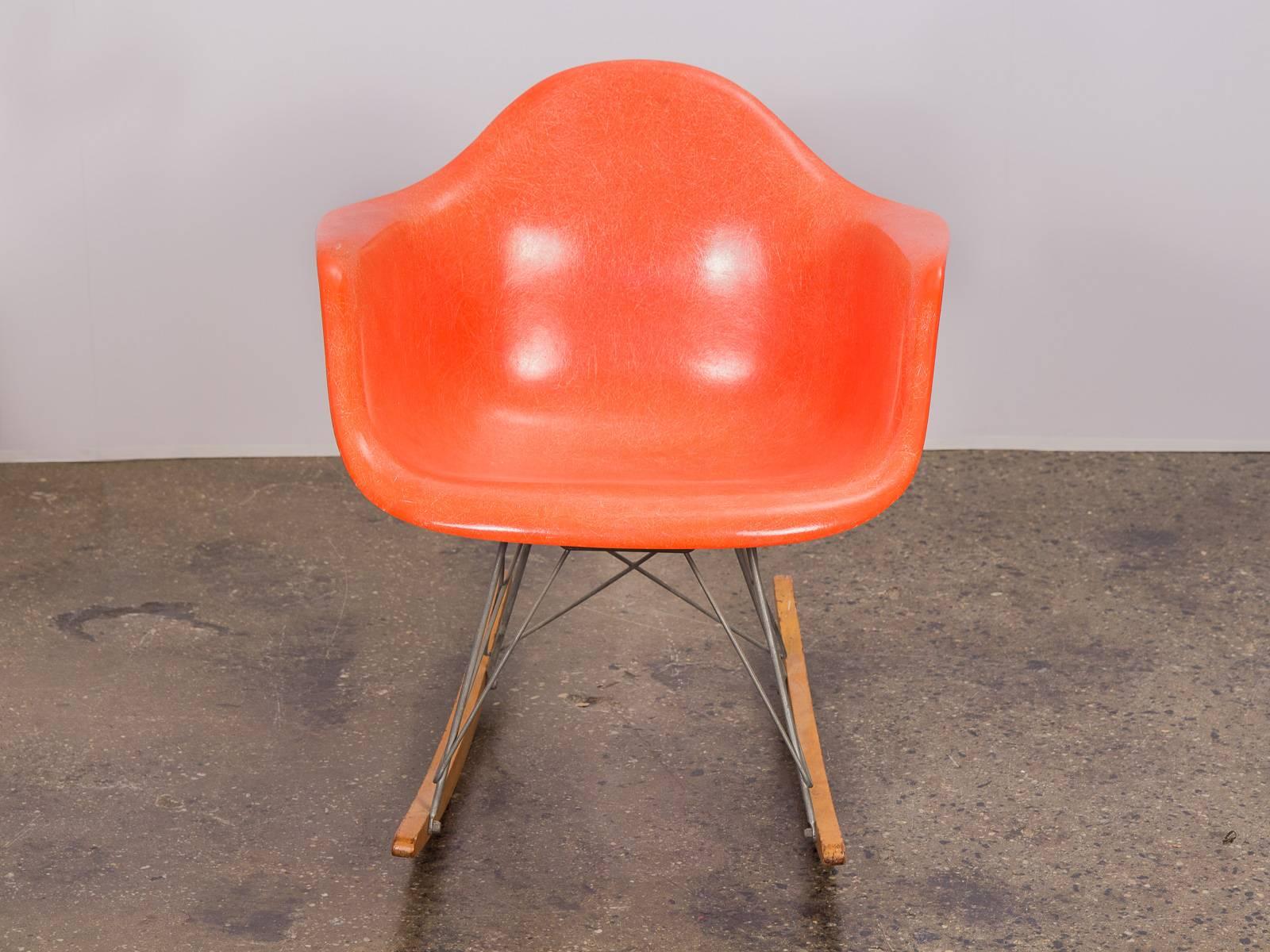 Vintage orange fiberglass armchair shell on a third generation, birch runner rocker base for Herman Miller. Shell is distinctly thready, with incredibly clean edges with no chipping. Some age appropriate wear to the vintage rocker base, but is in