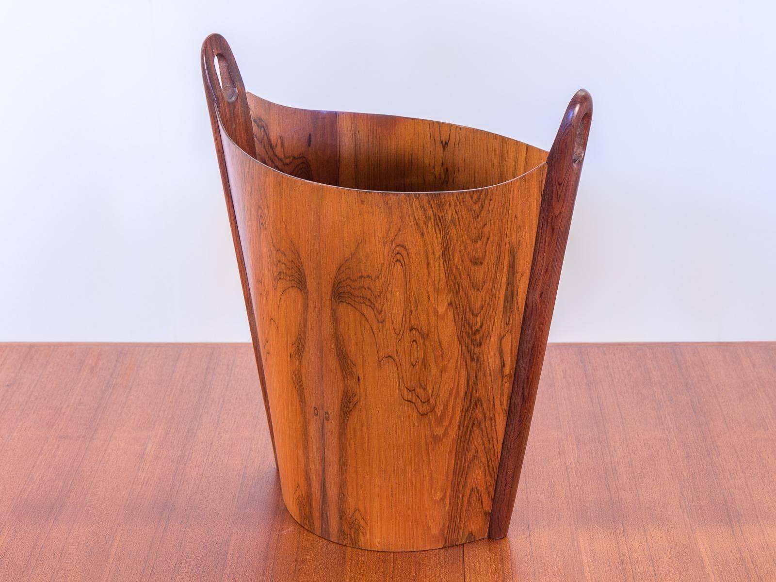 Gorgeous rosewood wastepaper basket designed by Einar Barnes for P.S. Heggen. The gleaming bentwood form displays an alluring grain pattern. The sculpted handles and unique tapered shape are in excellent vintage condition. Sure to impress co-workers